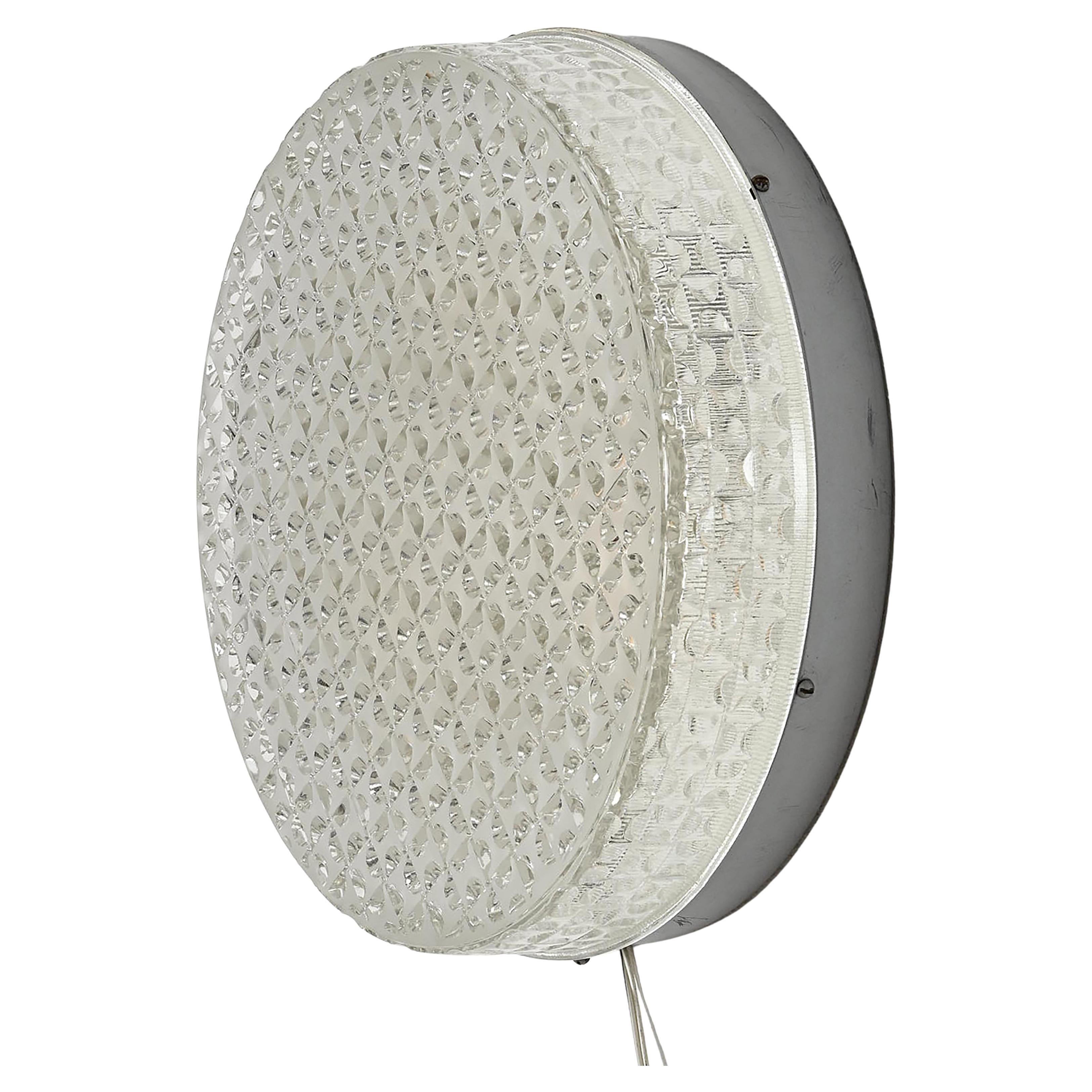 Raro J.T. Plafón o aplique Kalmar Trimline. Estructura de acero provista de 3 enchufes cerámicos E27 de hasta 100 vatios cada uno, cubierta con una pantalla redonda de cristal grueso de diseño geométrico. 
Dos piezas disponibles. Precio por lámpara.