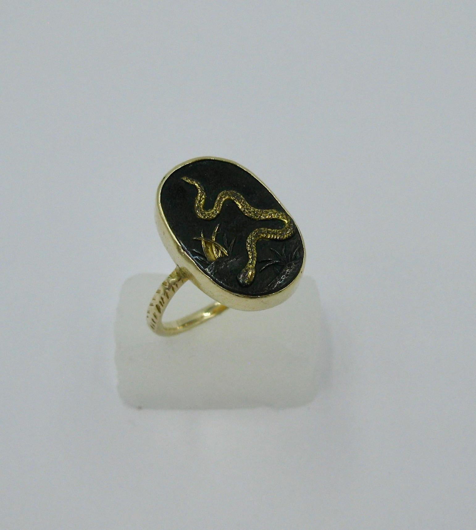 This is a very rare ring depicting a snake traveling through the grass in the historic Japanese art form of Shakudo, in 14 Karat Gold.   The Shakudo pieces originated in the Samurai period in Japan and were created by esteemed artists who made
