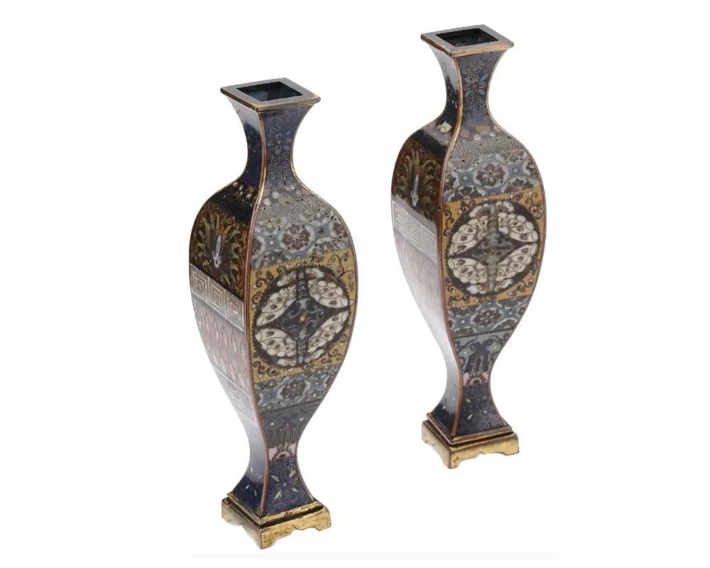 A pair of rare identical Japanese unusual shaped enamel over brass bud vases. Each vase has a sphere shaped body with a narrow neck and a narrow base. The exterior of the vases are enameled with polychrome medallions with symmetrical images of