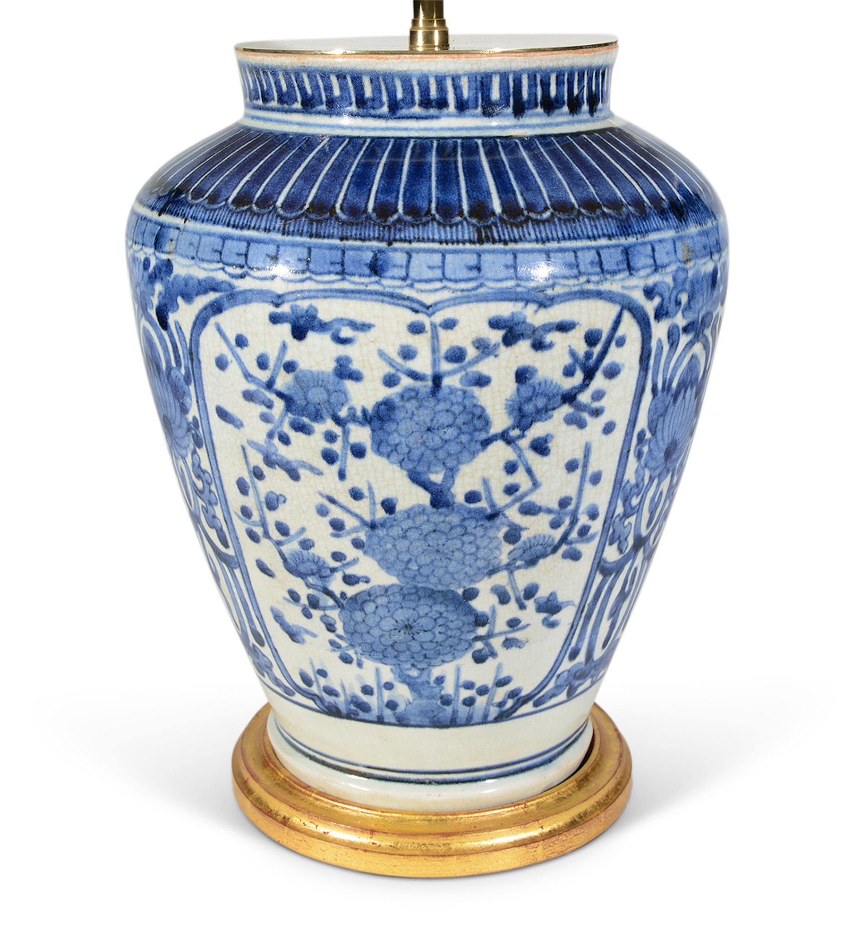 A fine and rare early 18th century Japanese Arita baluster vase, painted in tones of blues on a white background, the principal panels decorated with sprays of flowers and foliage, now mounted as a lamp with hand gilded turned base.

Height of vase: