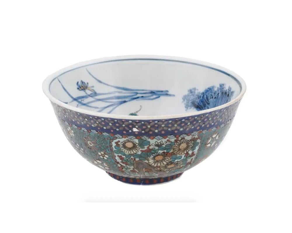 A rare antique Japanese footed enamel over porcelain bowl. The exterior of the bowl is enameled with polychrome floral, foliage and swirl motifs made in the Cloisonne technique. The interior of the bowl is adorned with a hand painted image of