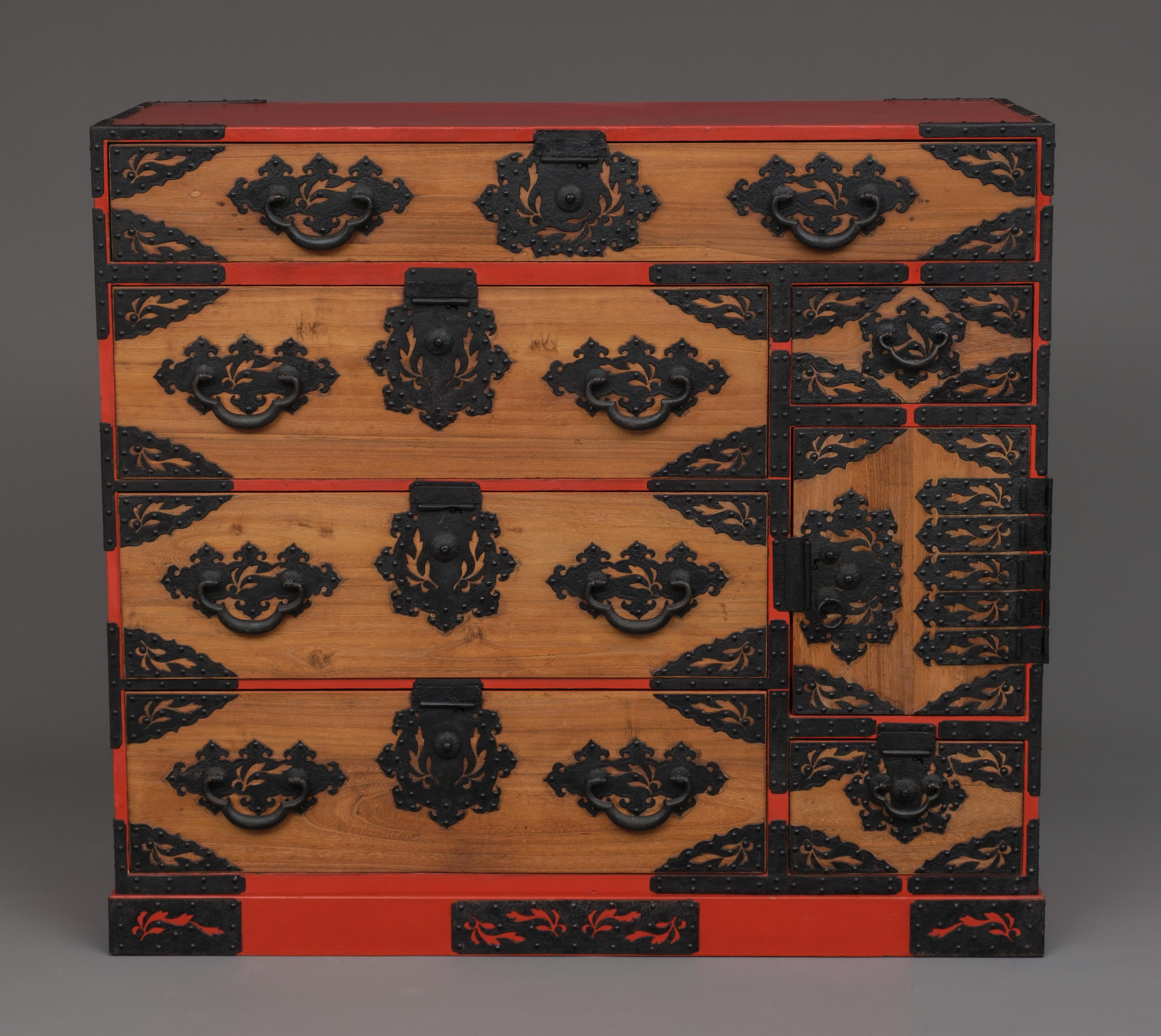 Rare and richly adorned wooden Kyûshû ishô'dansu (cabinet of drawers) in a single section, on a plinth. 
Fully restored, cleaned and waxed.

The drawer faces are made of indigenous kiri (paulownia) wood varnished in a sought after warm brown hue, a