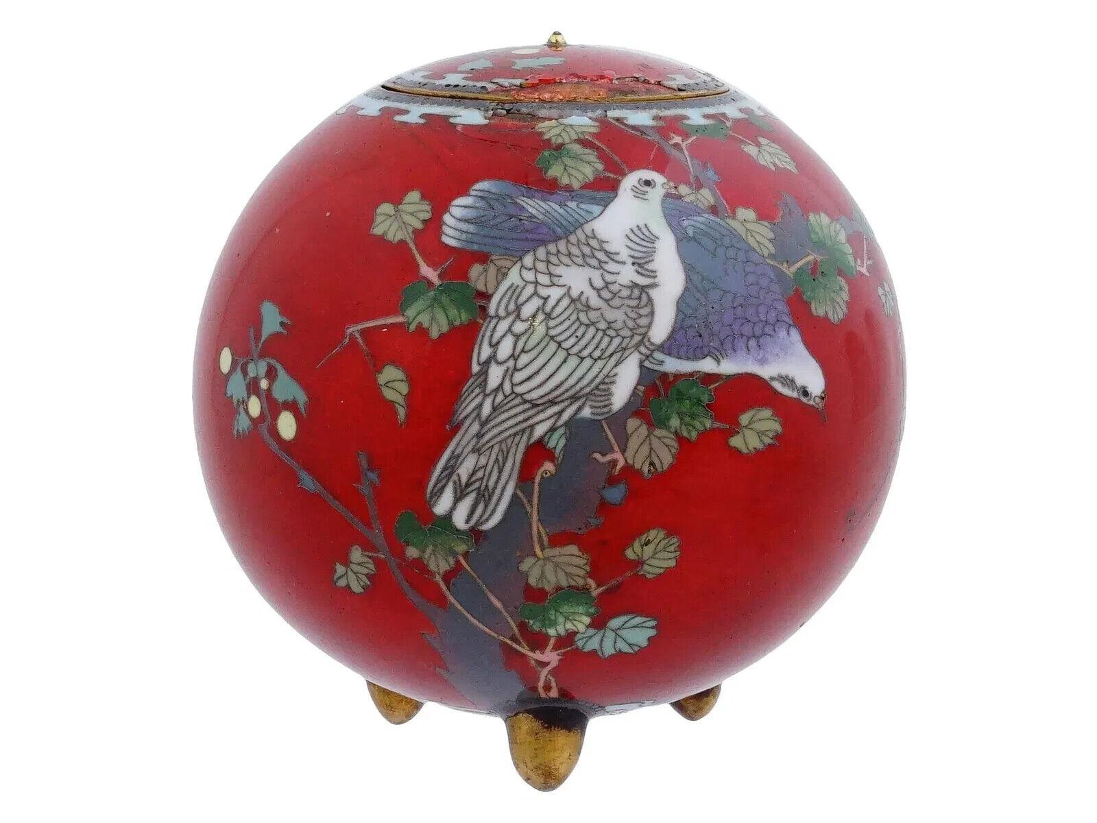 A rare antique Japanese late Meiji Era tripod and covered enamel copper censer. Circa: late 19th century to early 20th century. The sphere form censer koro is enameled with polychrome enamel images of two birds made in the Cloisonne technique on red