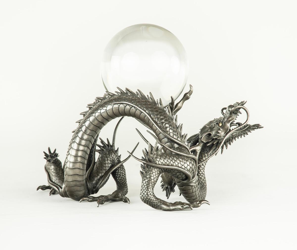As part of our Japanese works of art collection we are delighted to offer this very rare exceptional quality Meiji Period (1868-1912), cast shibuichi okimono of a writhing dragon resting a large glass sphere upon his back, the sphere representing