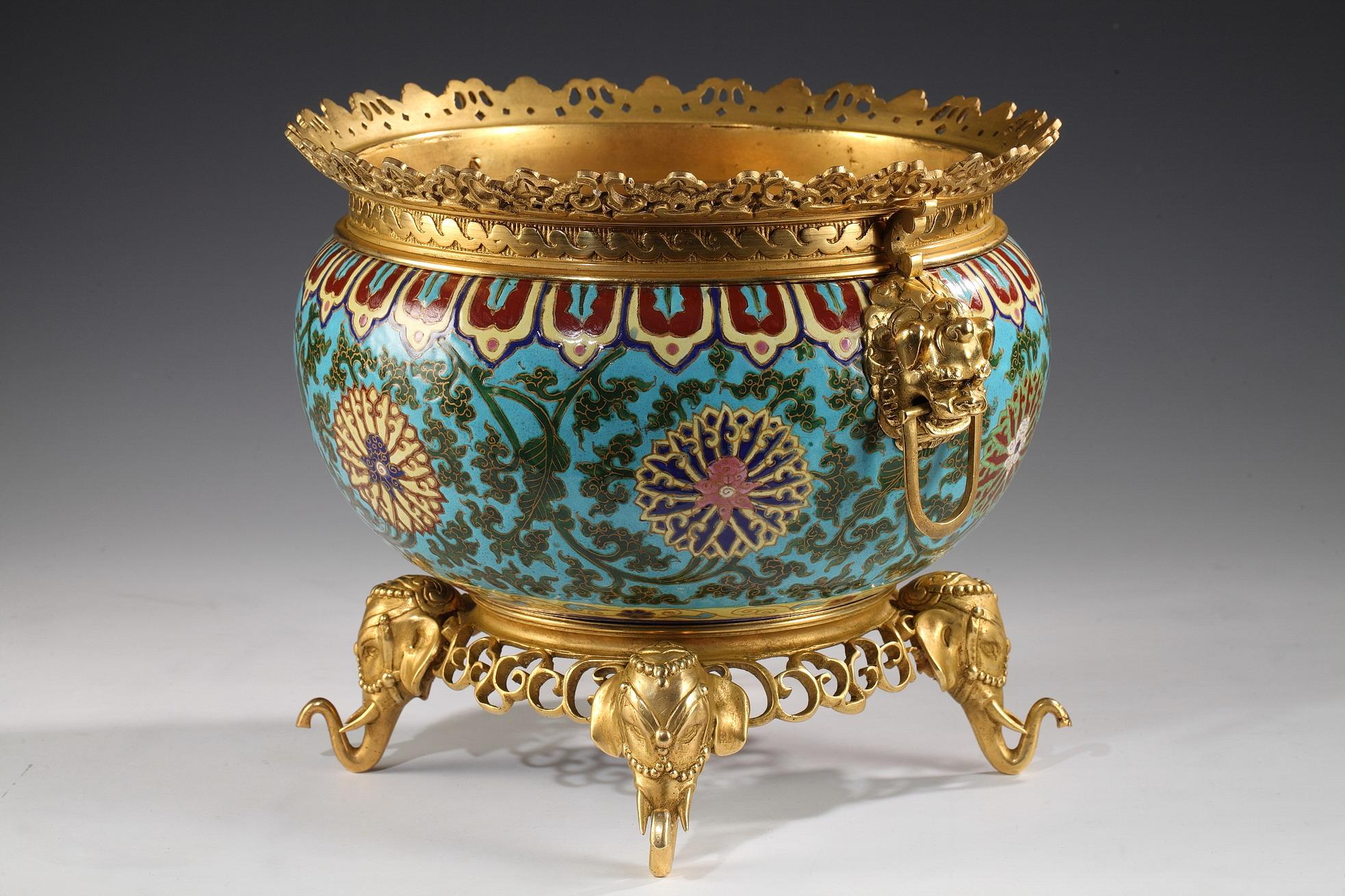 This circular planter in enamel ceramic, by L'Escalier de crystal, is embellished with a floral and vegetal polychrome décor upon a celestial blue background. Beautiful chiselled and gilded bronze openwork mounting of Fô dogs forming the handles.