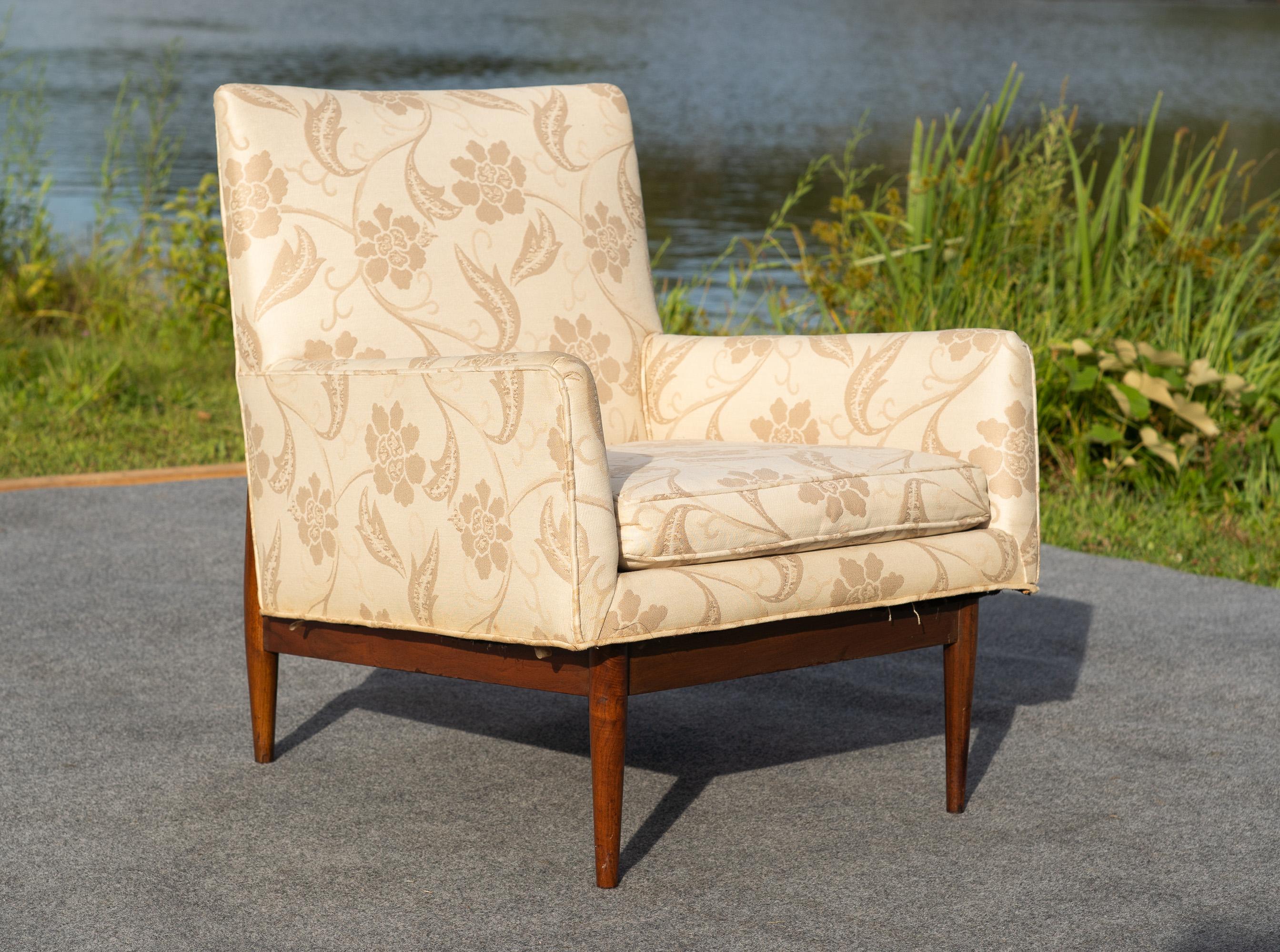 Designed by Jens Risom, this lounge chair was made exclusively for the model year 1953. It features a frame of solid carved walnut and is upholstered in a light floral fabric. Then design also features the typical Risom style of making chairs super