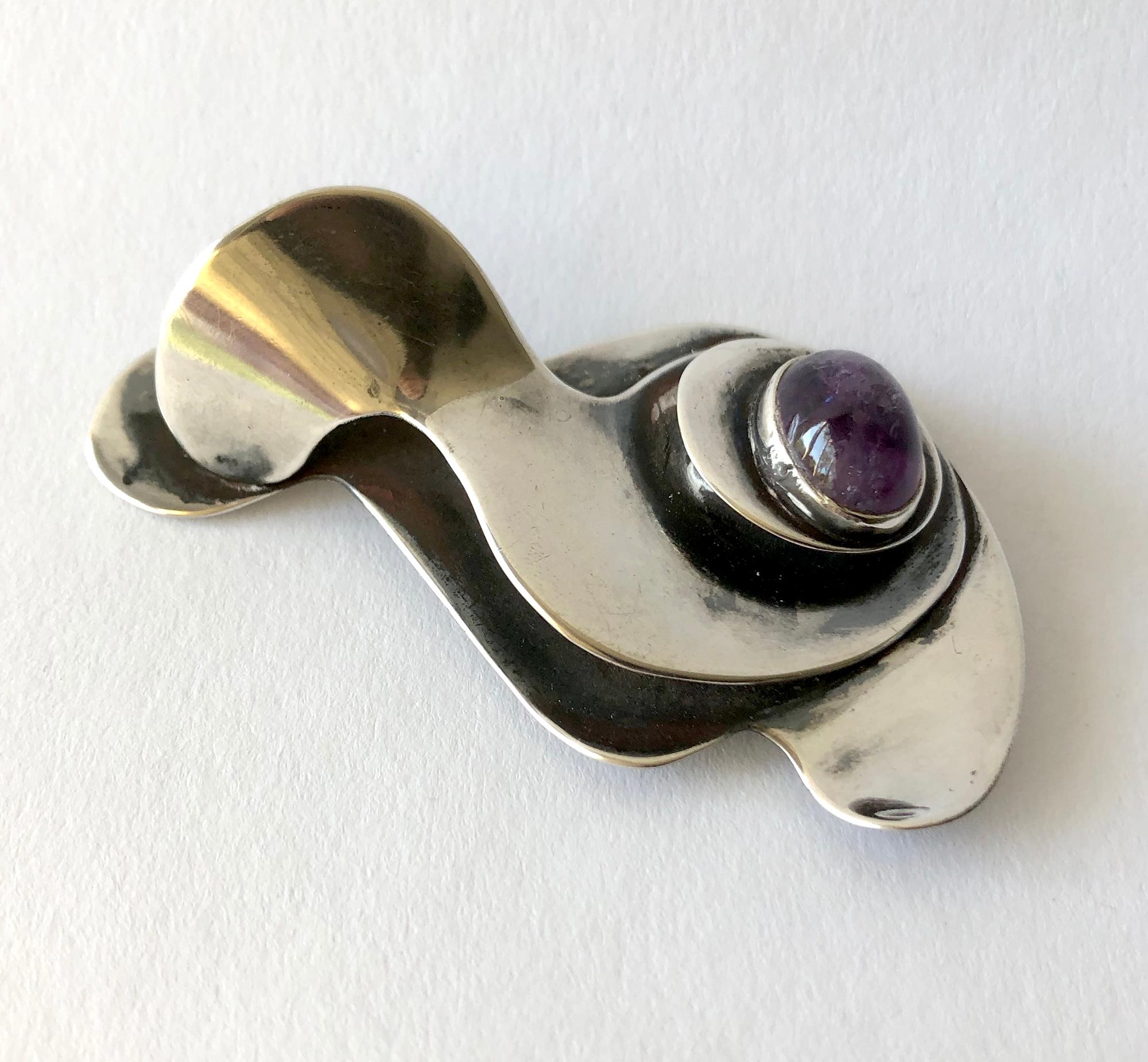 An early multi layered sterling silver and amethyst brooch designed by Joan Hurst and Jill Kingsbury of New York City, New York.  This is a large example of their work and has surrealist influence as seen in works by Sam Kramer. The brooch measures