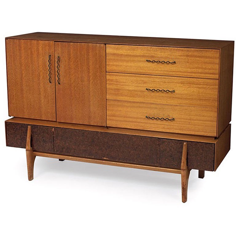 This Mid-Century Modern buffet or credenza by John Keal for Brown Saltman features three storage drawers and a cabinet behind a pair of double doors. The unit rests on a sculptured large center drawer.

 