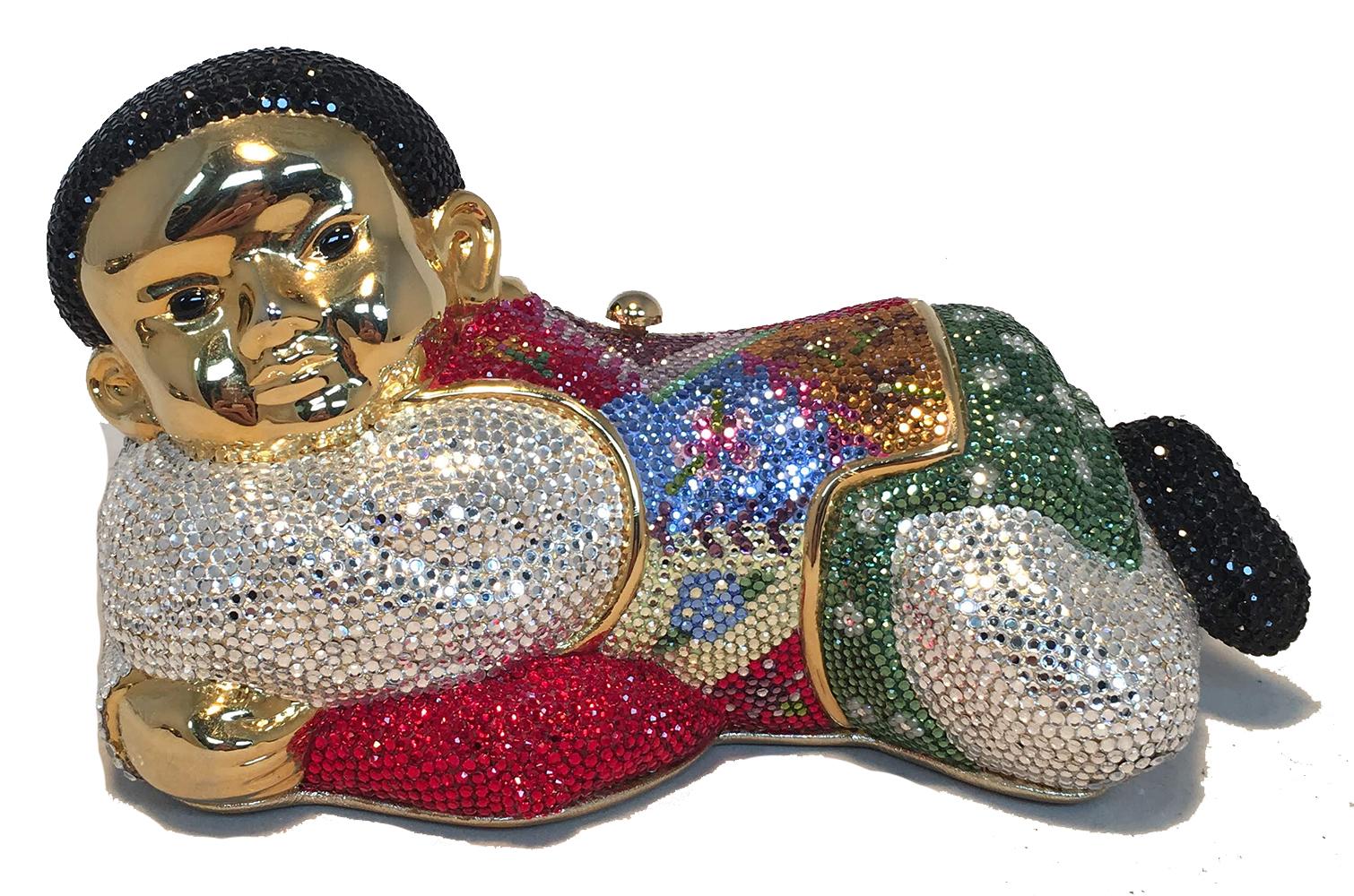 Collectible JUDITH LEIBER sleeping boy minaudiere in excellent condition. Multi-colored Swarovski crystal exterior over a gold form. Side button closure opens to a gold leather lined interior that holds 2 small separate compartments and a hidden