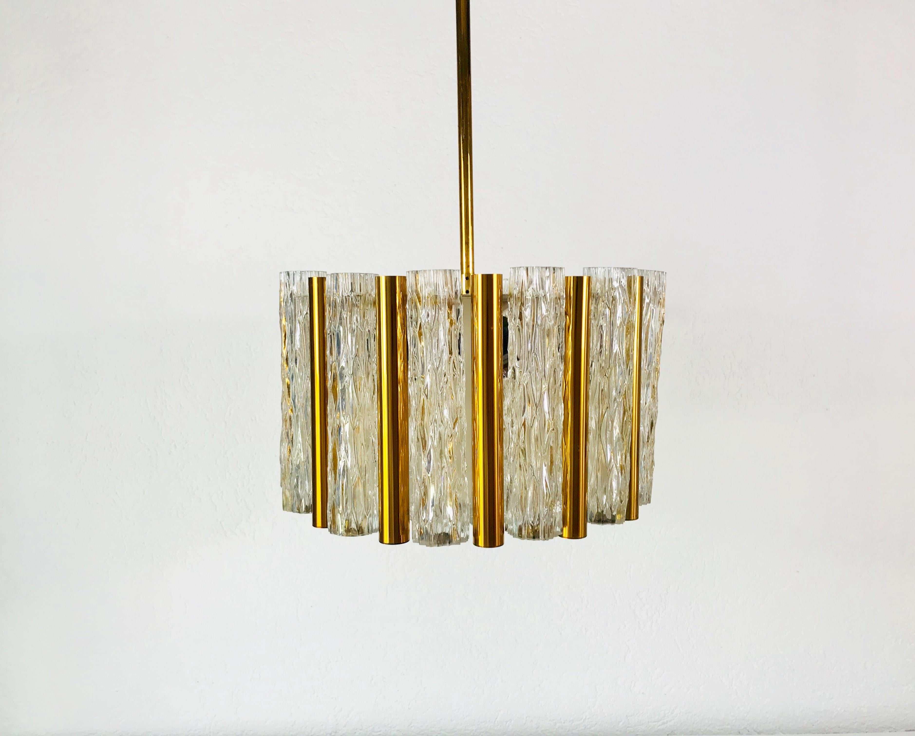 A Kaiser Leuchten ice glass chandelier made in Germany in the 1960s. It is fascinating with its rare tube glass shapes. A circular ice glass body on the bottom with 13 frosted glass tubes and 13 polished brass tubes. It has a very long brass