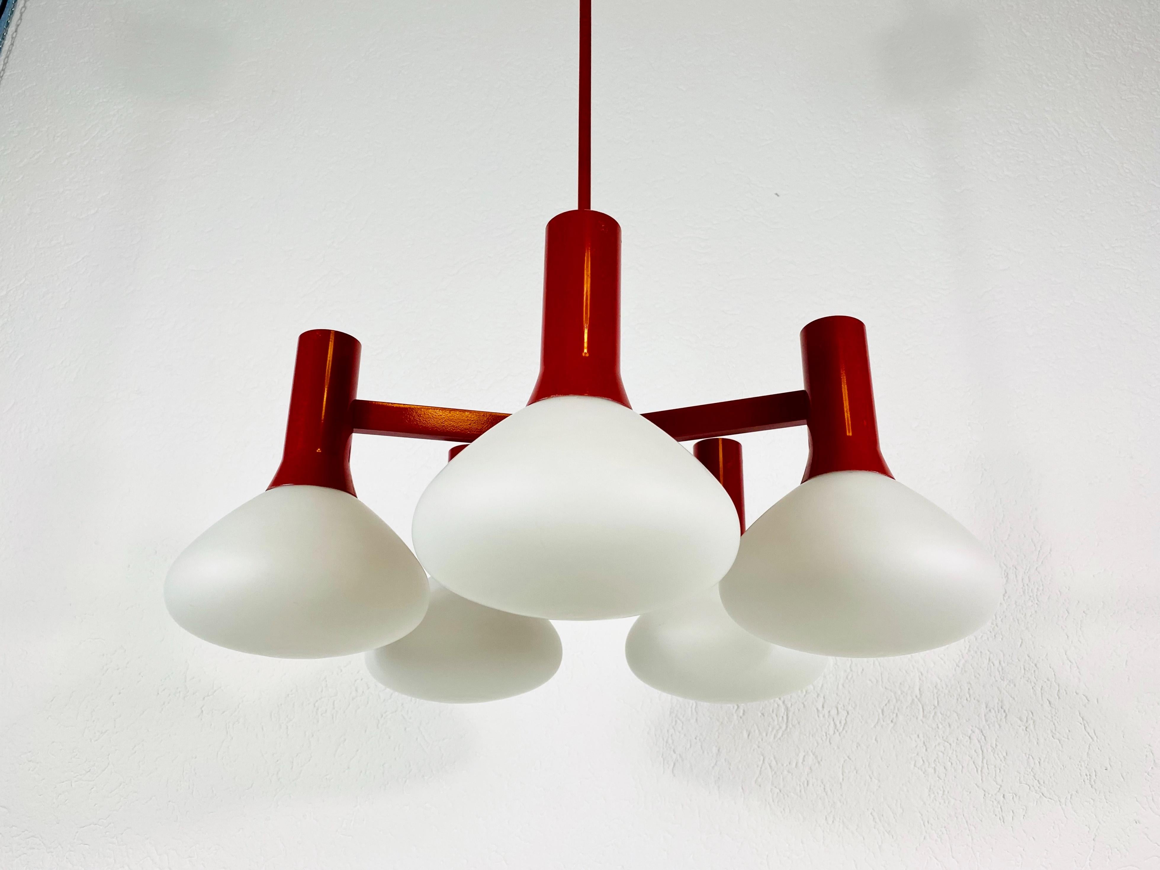 A midcentury chandelier by Kaiser made in Germany in the 1960s. It is fascinating with its Space Age design and five opaque balls. The red circular body of the light is made of full metal, including the arms.


The light requires 5 E14 light