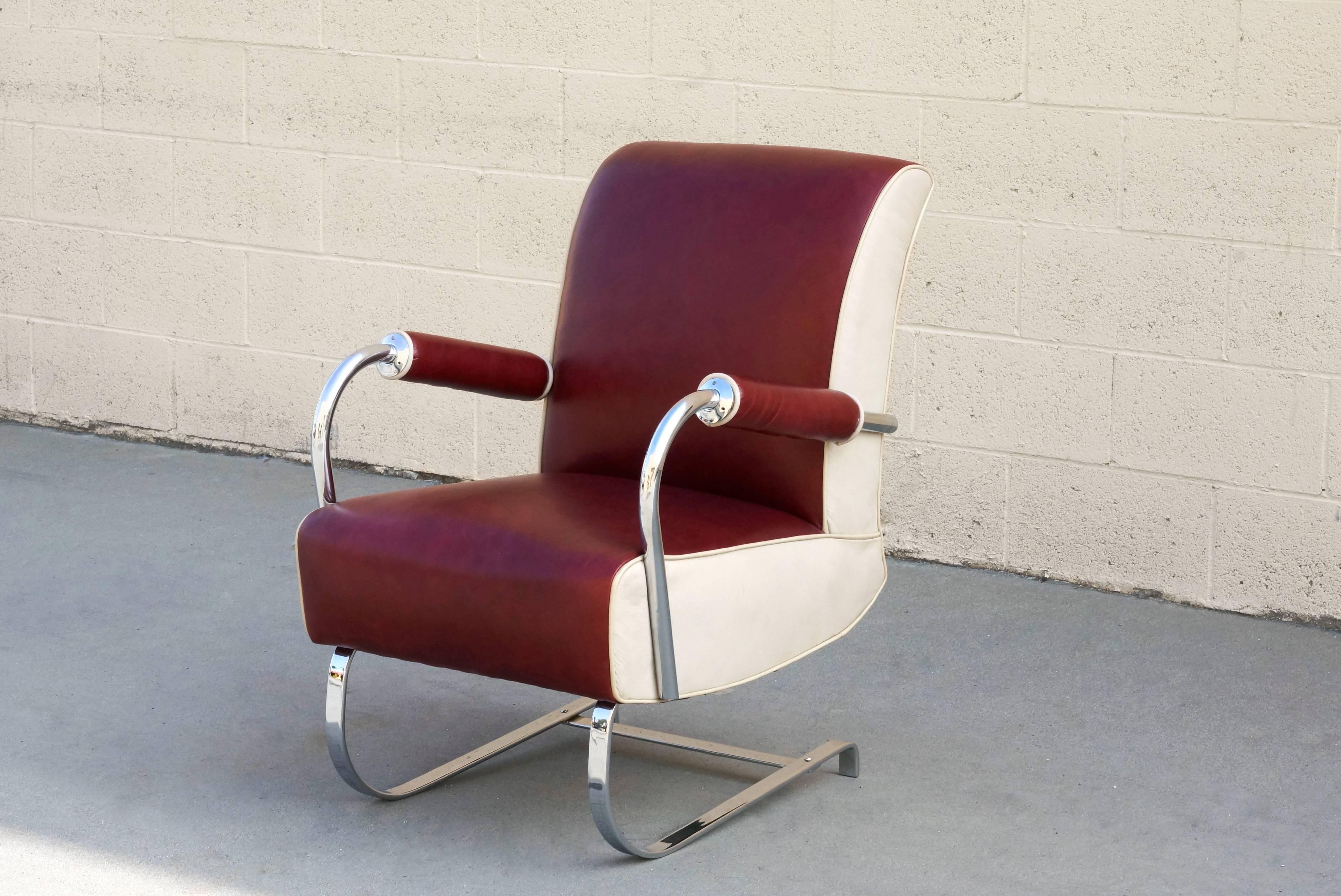 Uncommon and absolutely fantastic Kem Webber armchair, circa 1930s. Original tubular chrome arms and flat chrome base have been newly chrome-plated. Newly upholstered in two-tone cherry red and cream leather. Very cool cyclical padded armrests. A