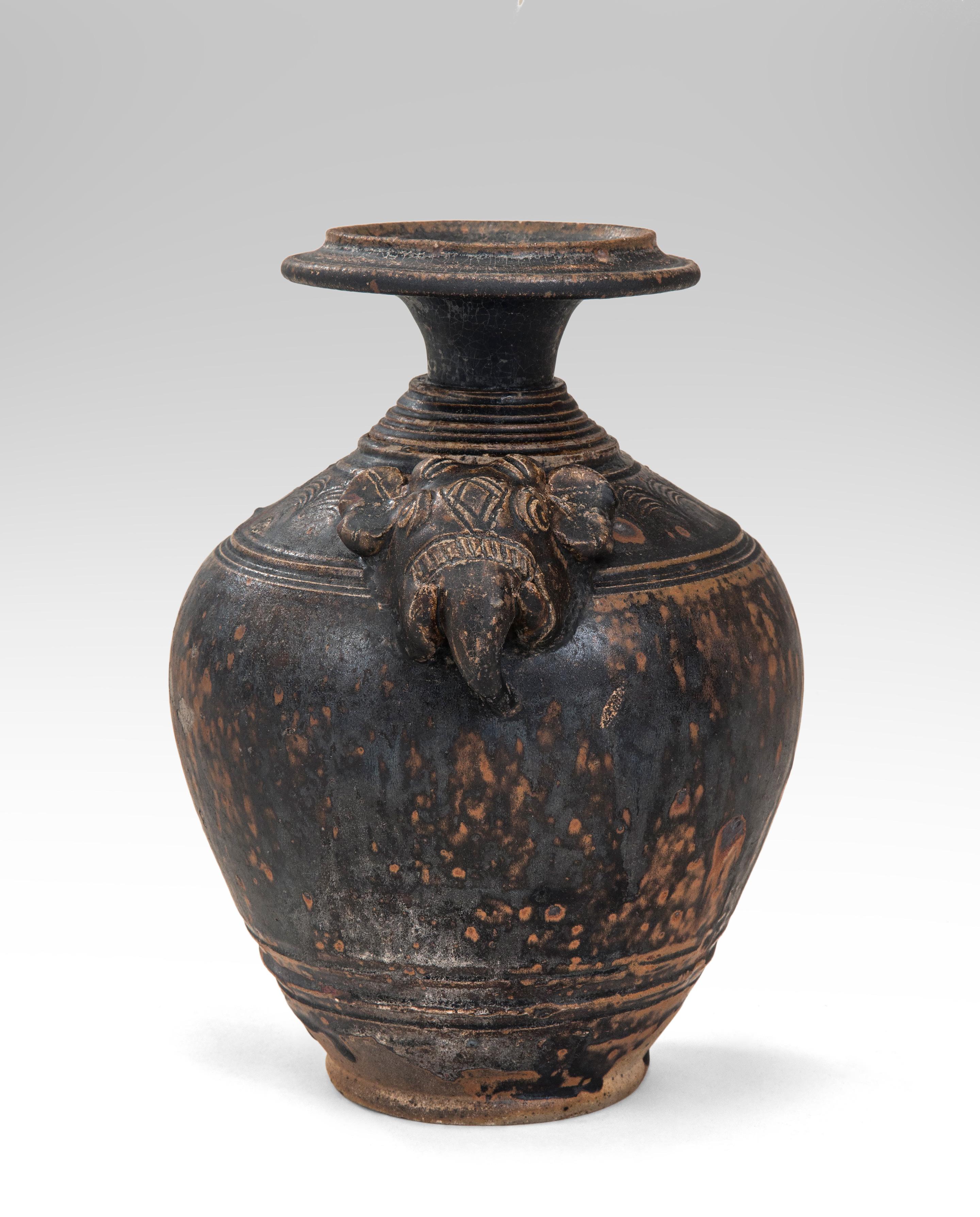 Rare Khmer Elephant Mask Earthenware Vase
Cambodian, 11th Century
The rich, dark-brown drip glaze and the expressive elephant head make this an outstanding example of early Khmer ceramics. The flaring mouth, above a multiple banded neck, the
