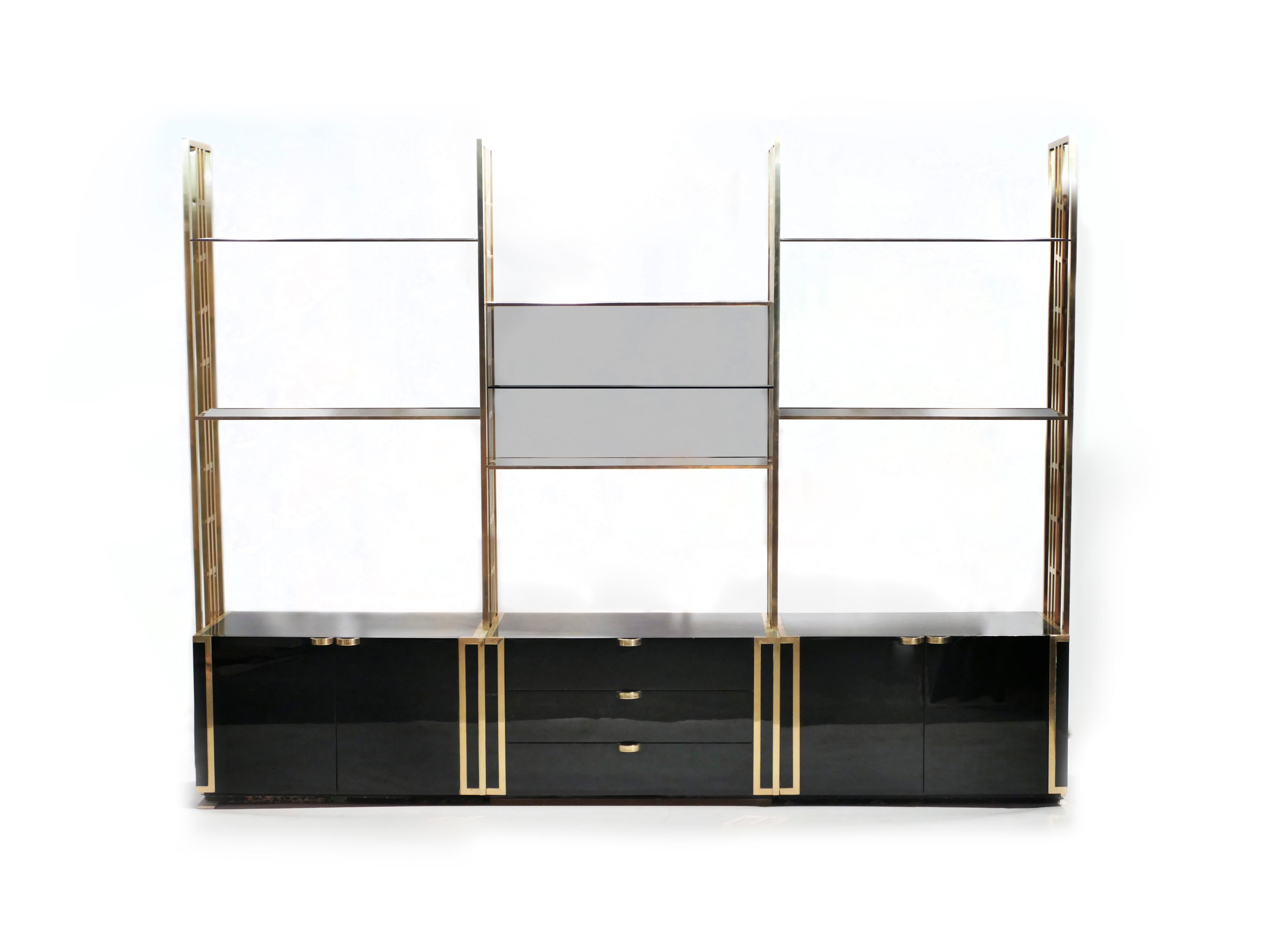 Functional and stylish, this shelving unit or bookcase has a brilliant brass structure, blue smoked glass shelves, and black lacquer cabinets. Designed by Kim Moltzer in the 1970s the piece was built and edited in France with superior quality.