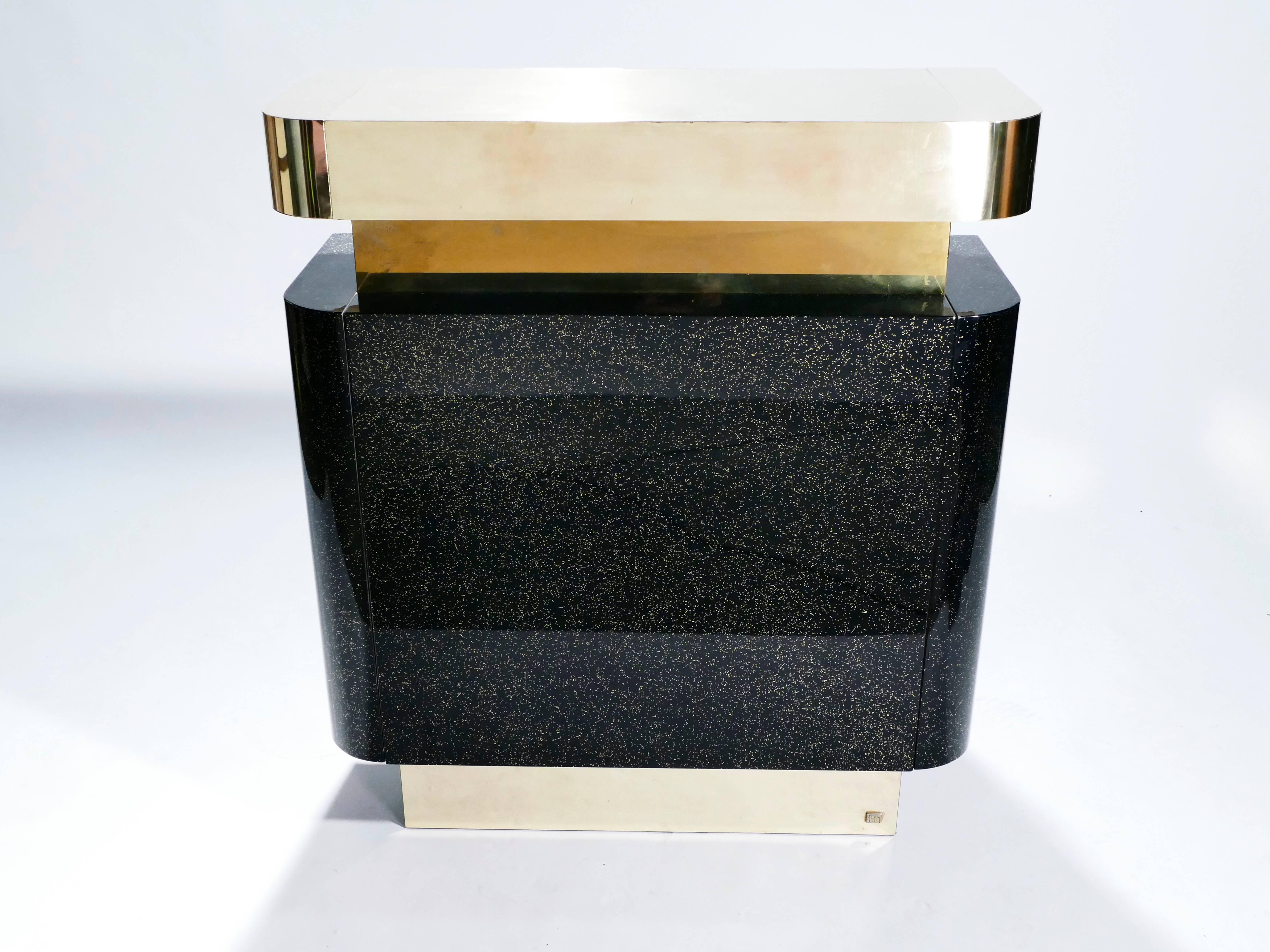 A bar for a standout look. This rare piece was designed by lighting and furniture designer Jean-Claude Mahey in the 1970s for firm Maison Romeo and displays all the trademark glam of the period. Brass and black lacquer are used in large, chunky