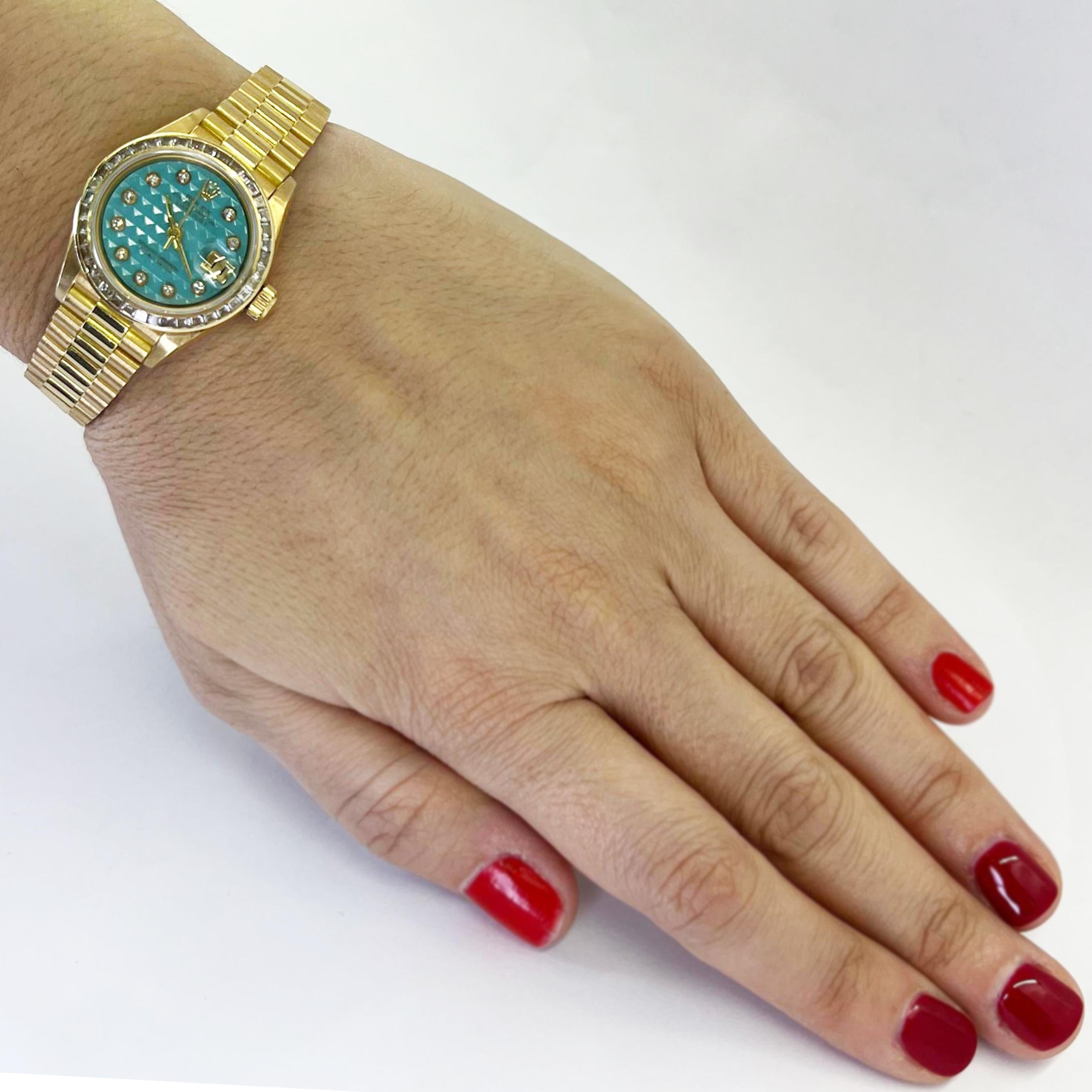 Pre-owned 26mm Rolex Datejust ladies automatic watch crafted in 18 karat yellow gold with factory baguette diamond bezel, turquoise pyramid stone dial, and President bracelet.

Model 69128, Circa 1986.

Includes 1 year timekeeping warranty.
