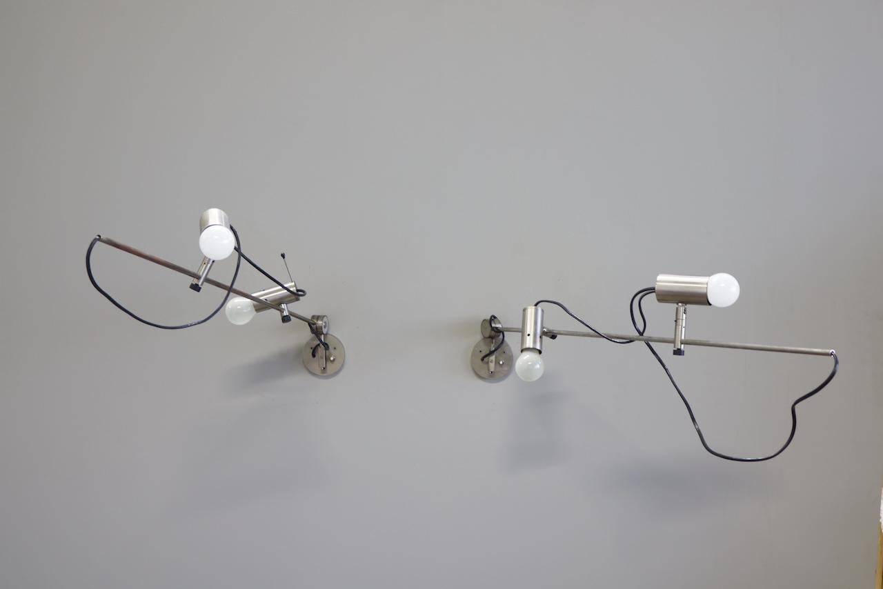 coppia di lampade da  parete modello 1144 disegnata da Tito Agnoli e prodotta da O-Luce. Il suo notevole design risale agli anni '50.  
Le lampade sono regolabili in tutte le direzioni. Lo stelo in metallo nichelato può essere regolato verso l'alto