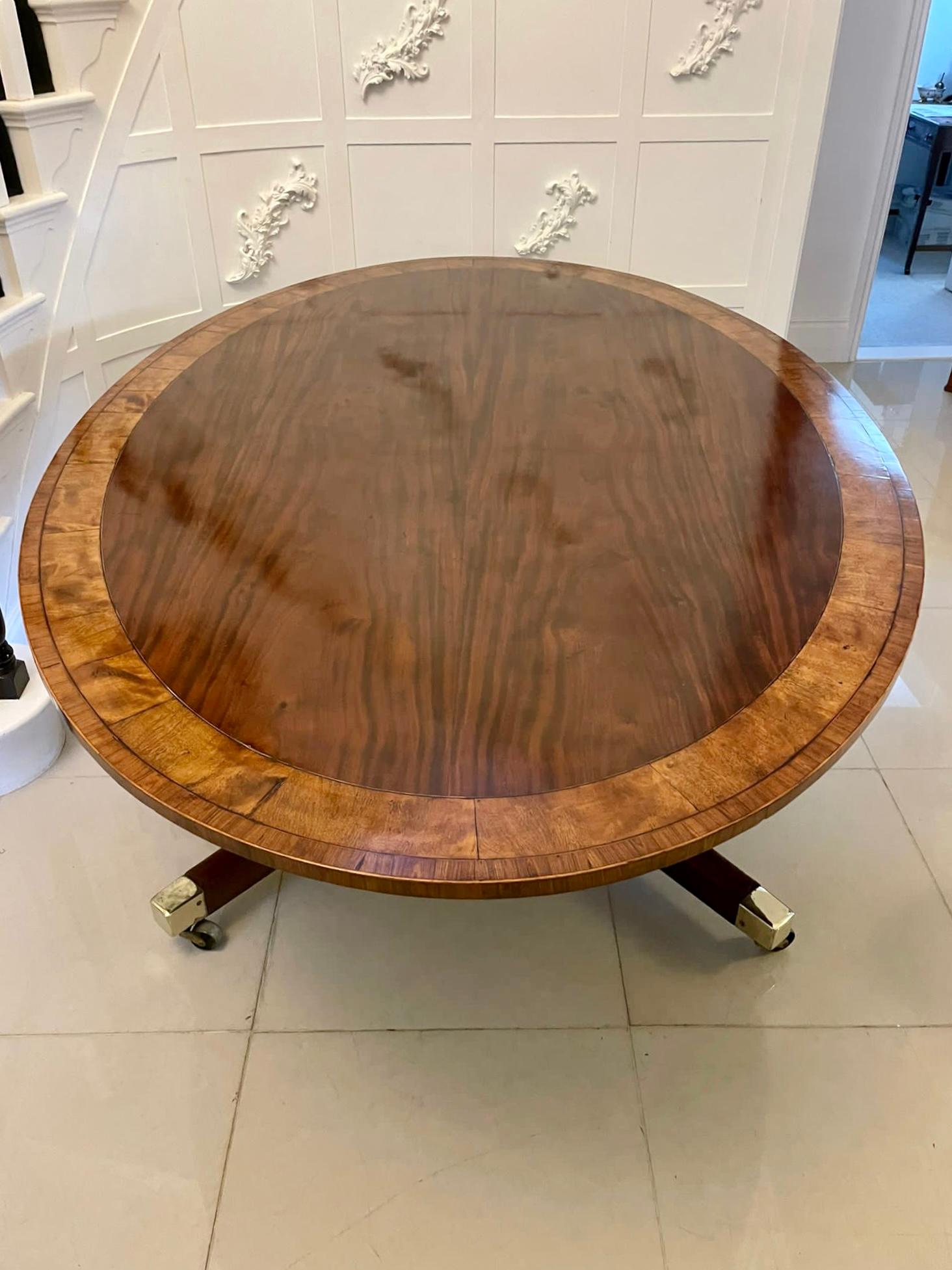 Rare large 10 seater antique George III oval quality mahogany dining table having a rare 7 feet oval figured mahogany tilt top crossbanded in satinwood supported on a fabulous turned pedestal column standing on four splayed inlaid mahogany sabra