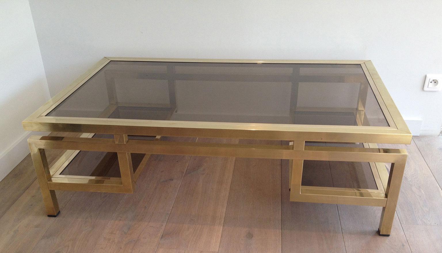 This rare important design coffee table is made of brass with smoked glass shelves. This is a work by famous French designer Guy Lefèvre for Maison Jansen. Circa 1970.