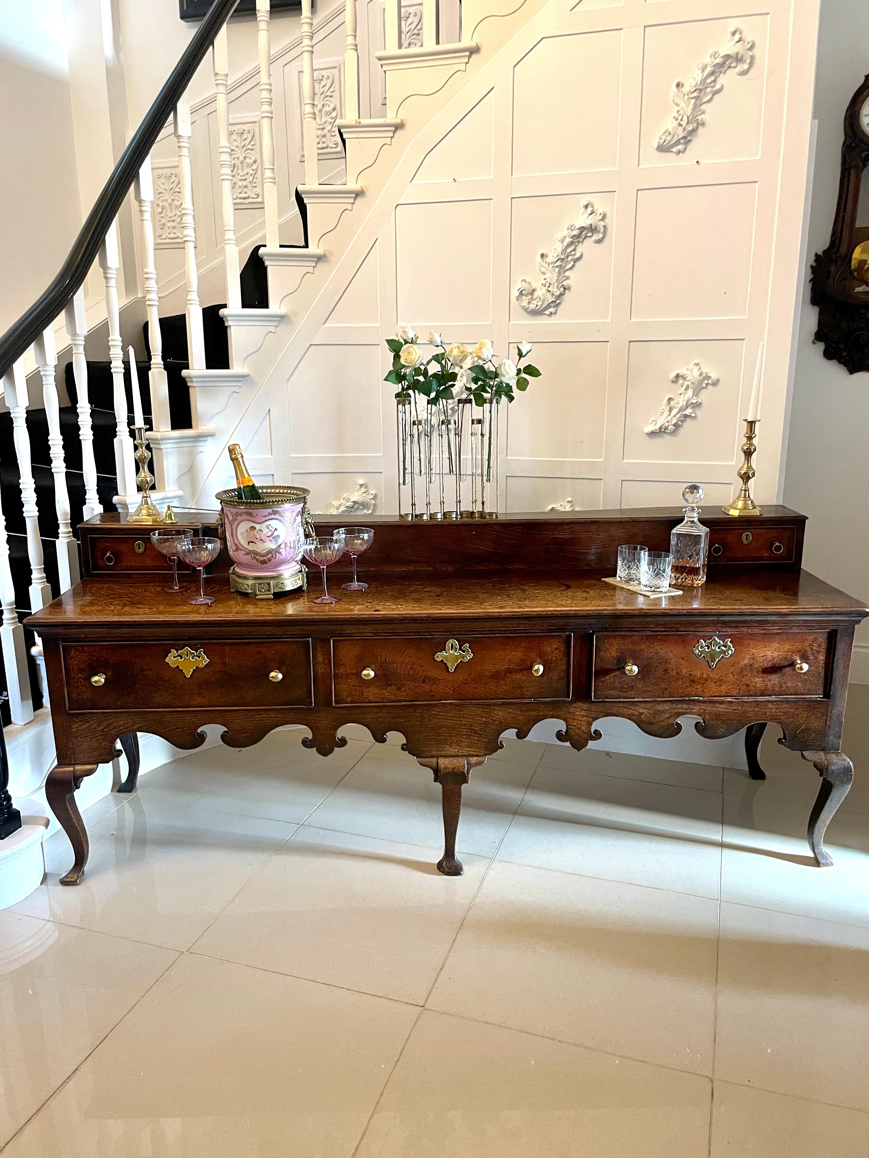 Rare large early 18th century antique quality oak dresser base having a low up stand with two drawers, wonderful quality oak top above three cockbeeded drawers with original brass handles and escutcheons.  It boasts a fabulous shaped frieze with