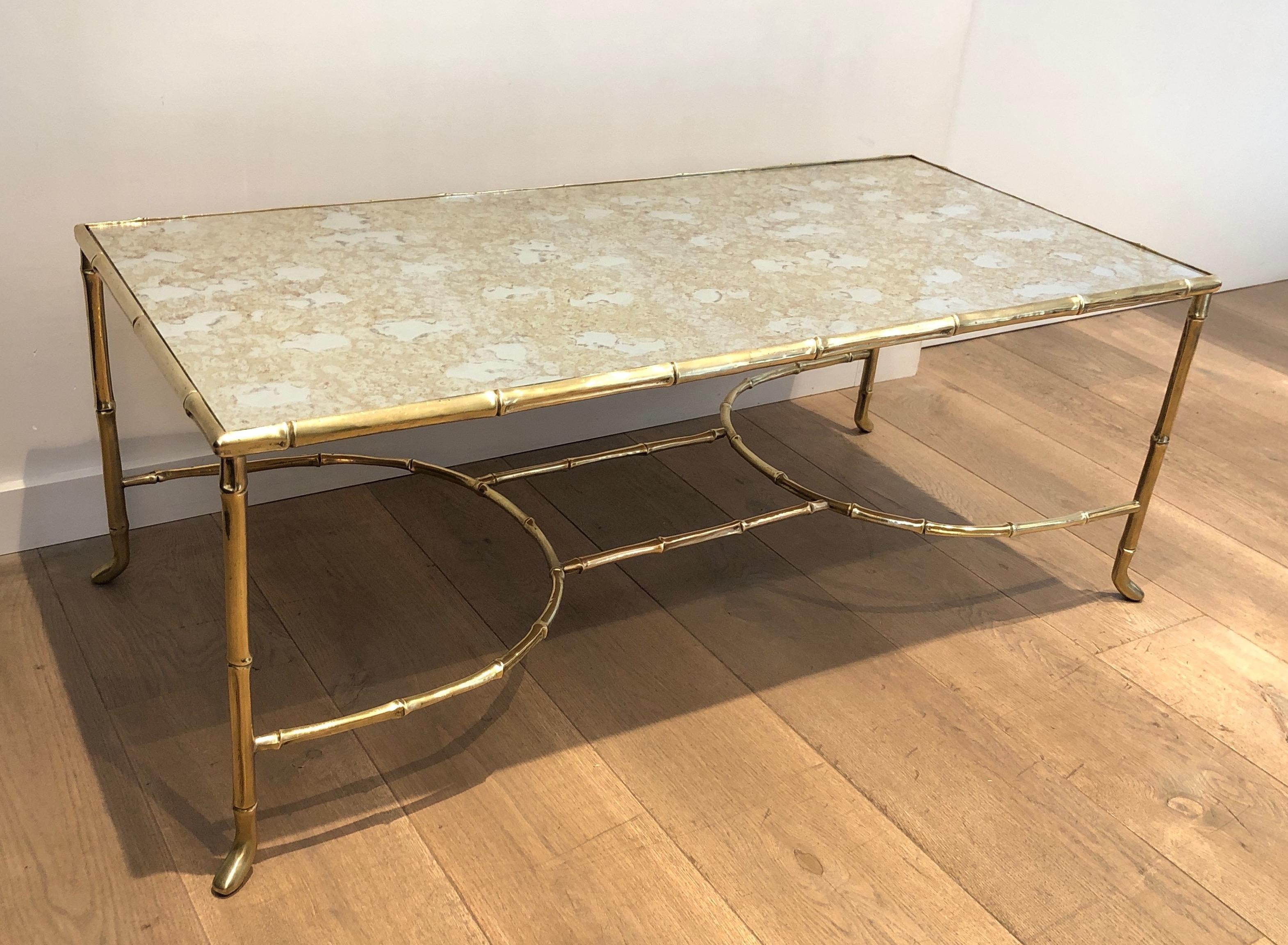 This rare large faux-bamboo coffee is made of bronze with a beautiful faux-antiques mirror top. This is a French work by Maison Baguès. Circa 1940.