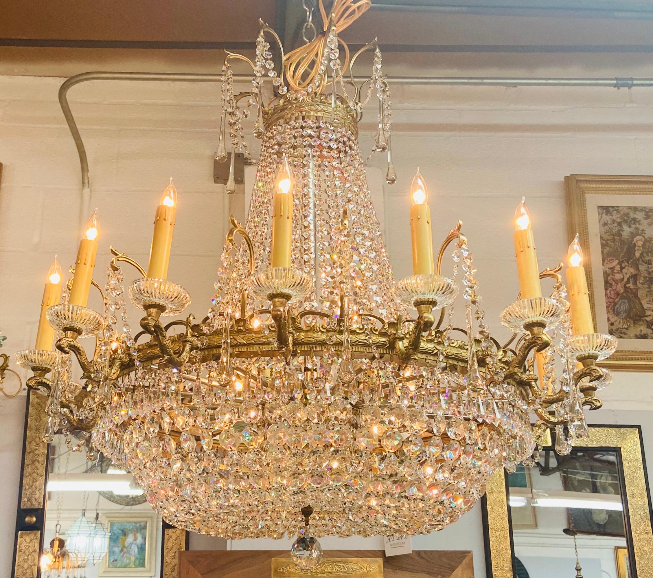 Magnifique et rare pièce du 19e siècle  Lustre de style Louis XVI en bronze et cristal avec 16 bras/chandeliers et électrifié à l'intérieur avec 7 candélabres.
Le lustre en forme de panier présente de multiples brins de cristal et une bande de