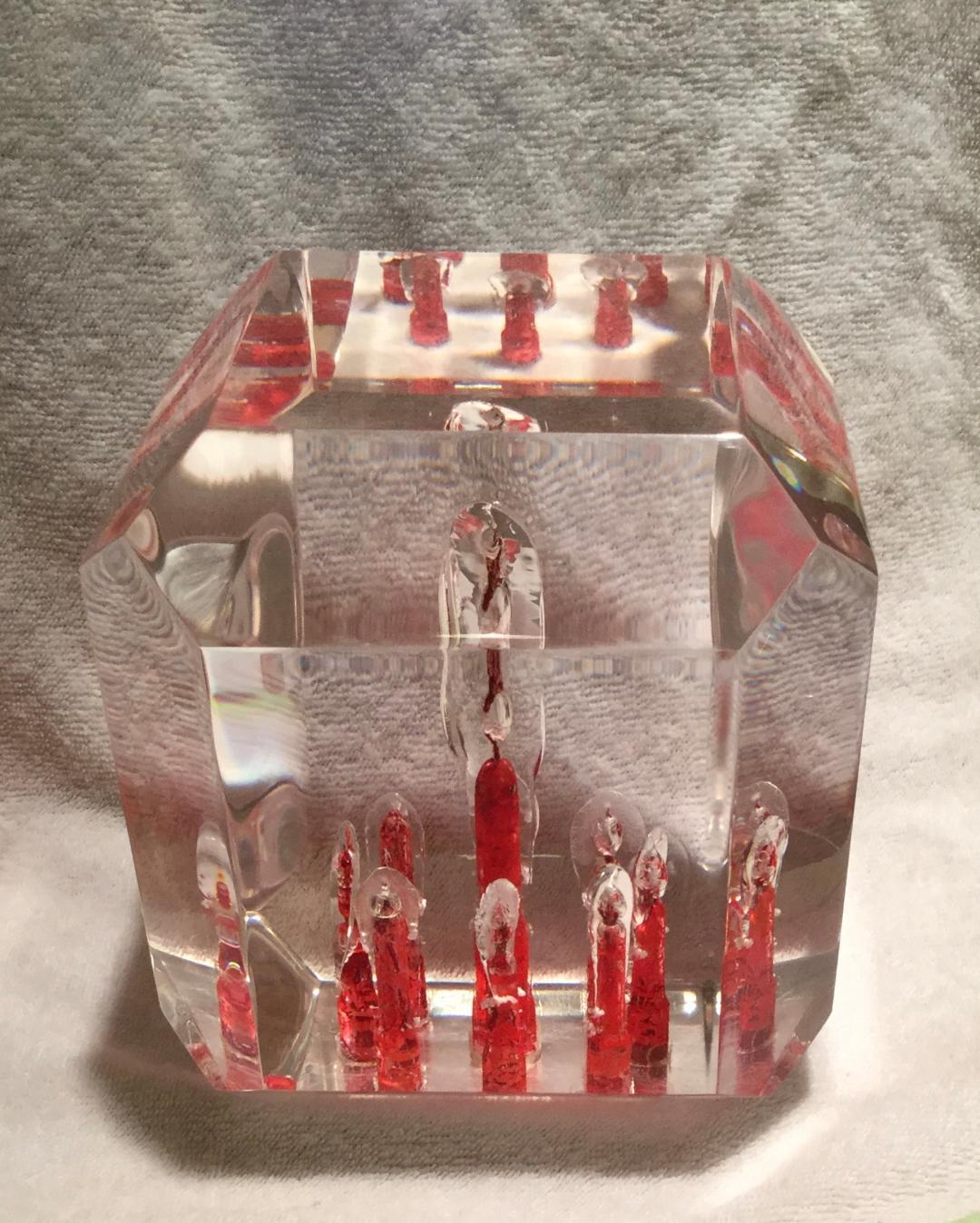 Rare mid-century paperweight cube executed in red and white Lucite or acrylic. This beautiful, one of a kind modernist piece has many facets and bevels all-over.
The inside has red looking candles with clear flames at the top and a large one in the