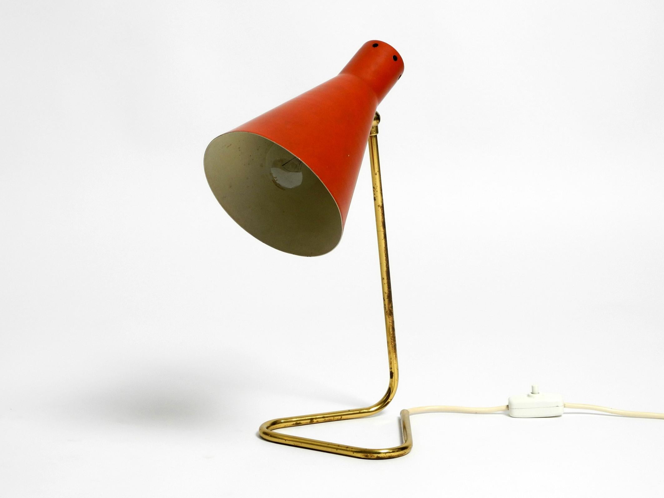 Large beautiful original 1950s table lamp. Probably from an Italian production.
Base and neck are made from a bent brass tube, with a cable run. The funnel shaped lampshade is made of metal lacquered in Brick Red. 
Very beautiful, typically