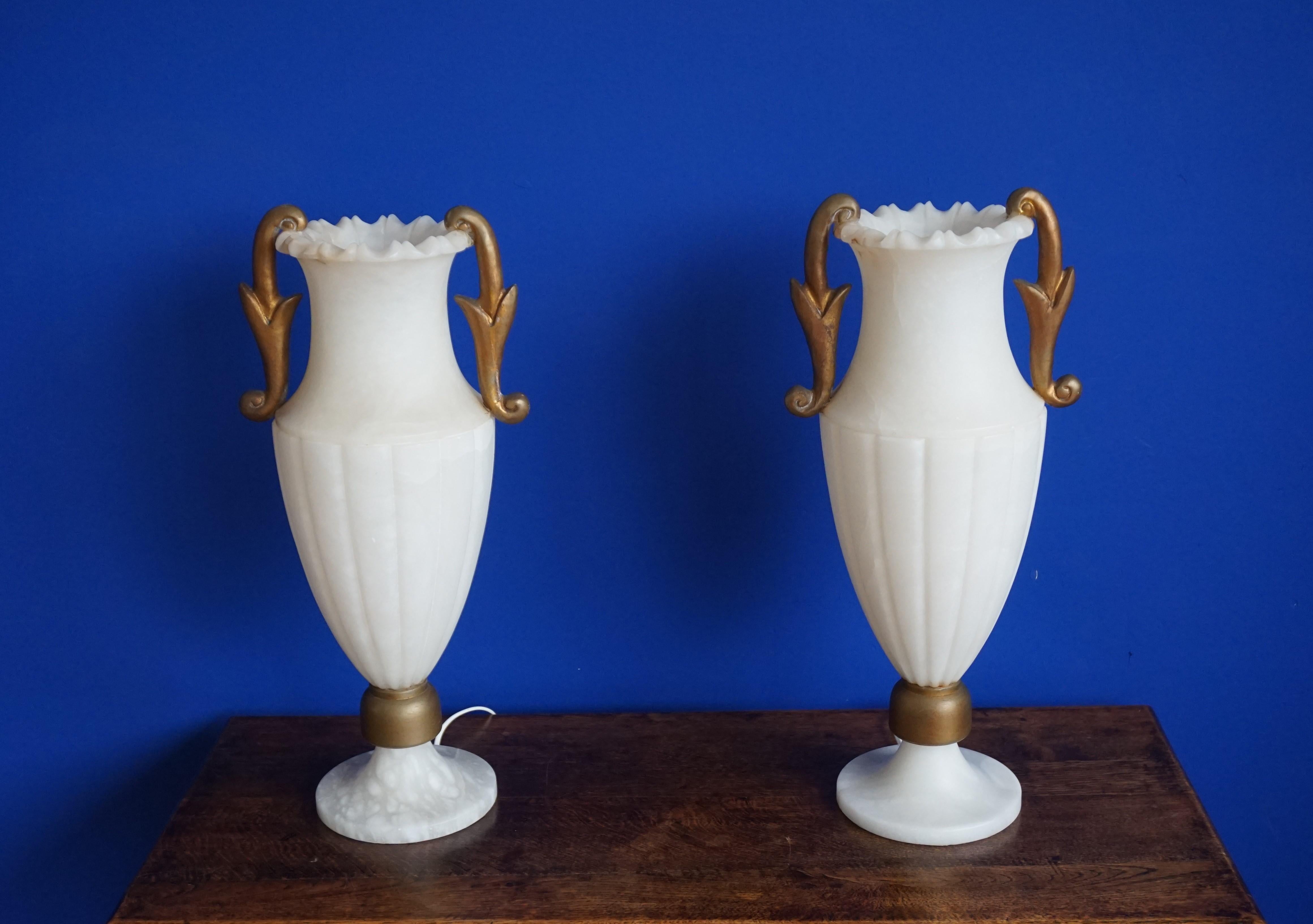 Midcentury era and large size pair of alabaster table lights.

This large and incredibly rare pair of Hollywood Regency table lamps could not be in better condition. All hand carved out of pure white alabaster rocks these two-piece table lamps are