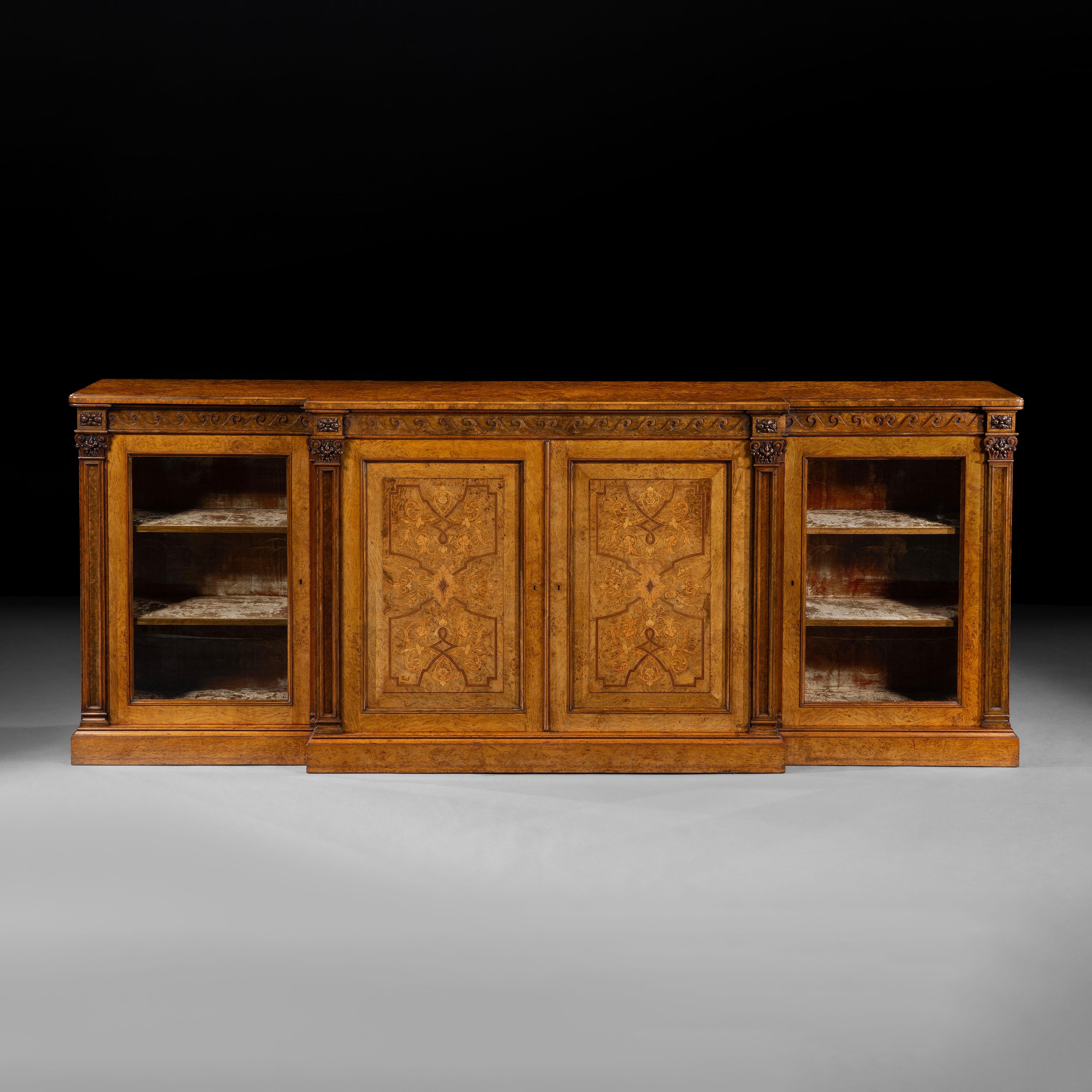 A Substantial Pollard Oak Library Bookcase
by Holland & Sons

Of low breakfront form, the whole bookcase constructed using a fine pollard oak and inlaid with a variety of specimen woods, having a continuous frieze with carved Vitruvian waves, below,