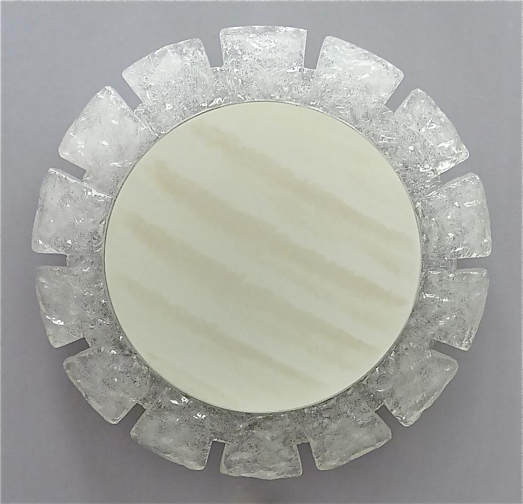 Large round backlit acrylic ice glass optic wall mirror made by Hillebrand, Germany circa 1960 to 1970. The cool mirror has a round starburst sunburst like acrylic ice glass optic frame which is mounted on a round white enameled and perforated metal