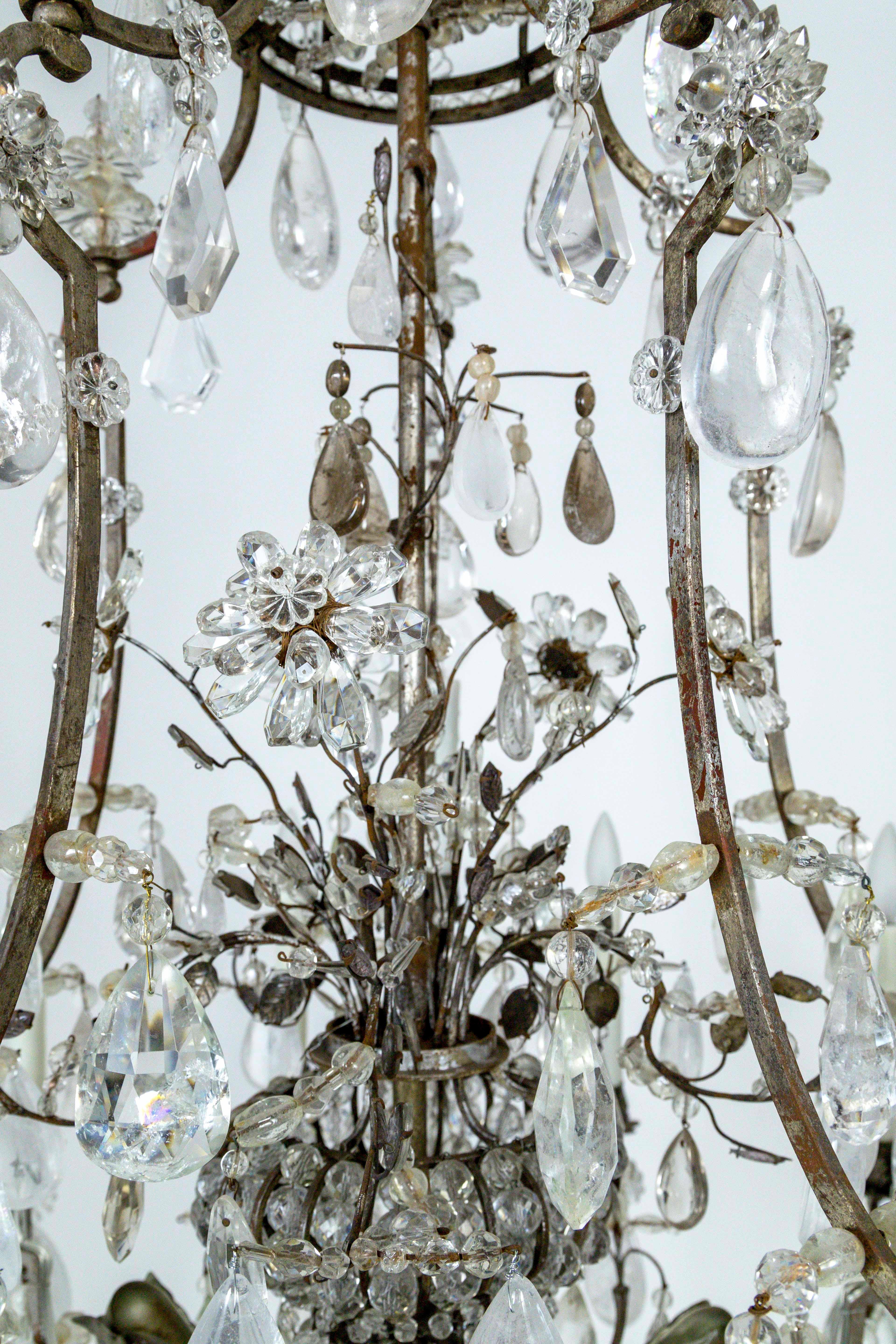An absolutely magnificent, rare, 20-light, silver-gilded bronze, rock crystal chandelier with impeccable balance and great scale. A birdcage design with an encased flower bouquet, the center column is a crystal beaded Amphora jar shape that holds