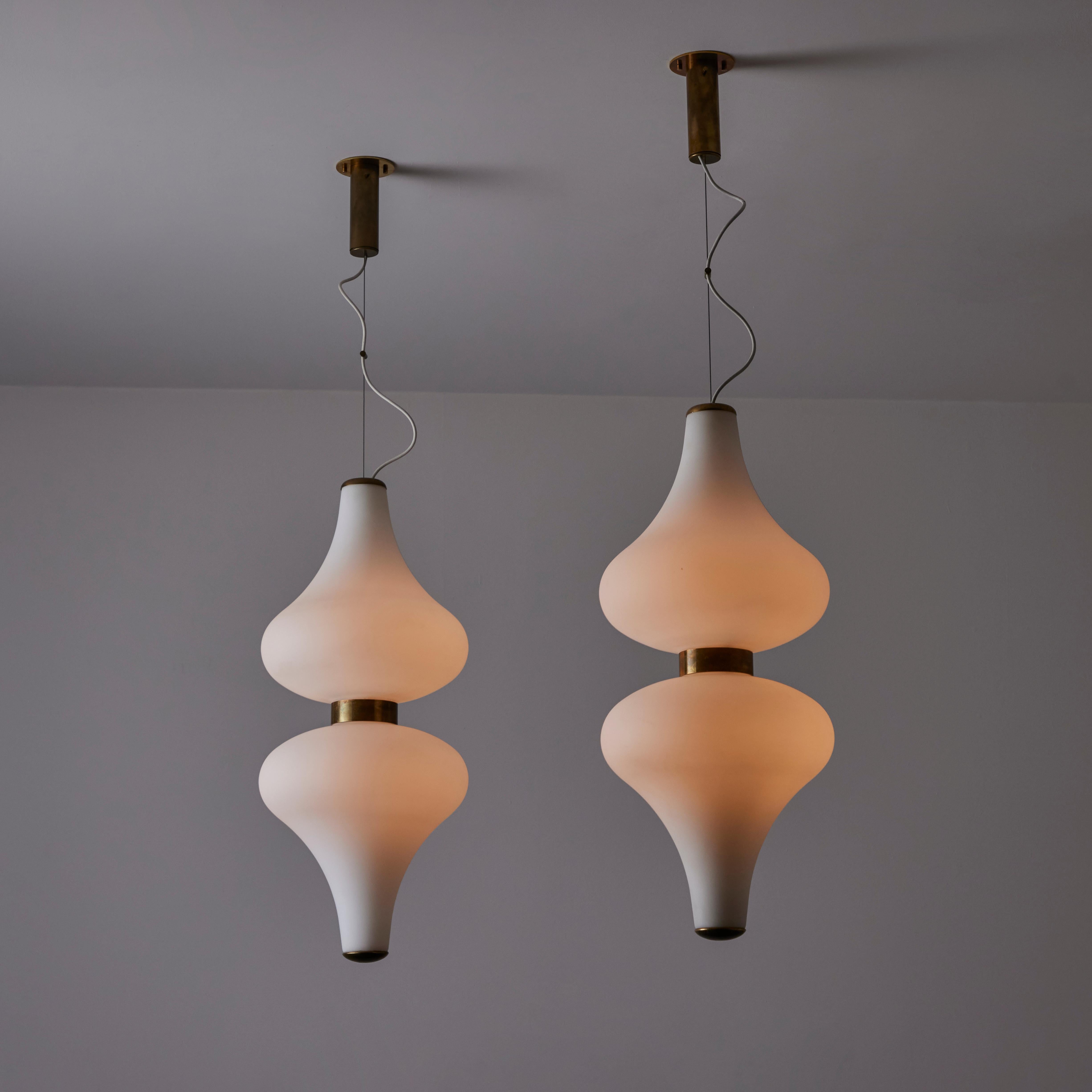 Rare Large Suspension Light by Stilnovo. Designed and manufactured in Italy, circa the 1960s. This rare double-sided pendant by Stilnovo features a stunning 360-degree tear drop milk glass shade on both sides of a circular brass clasp. We recommend