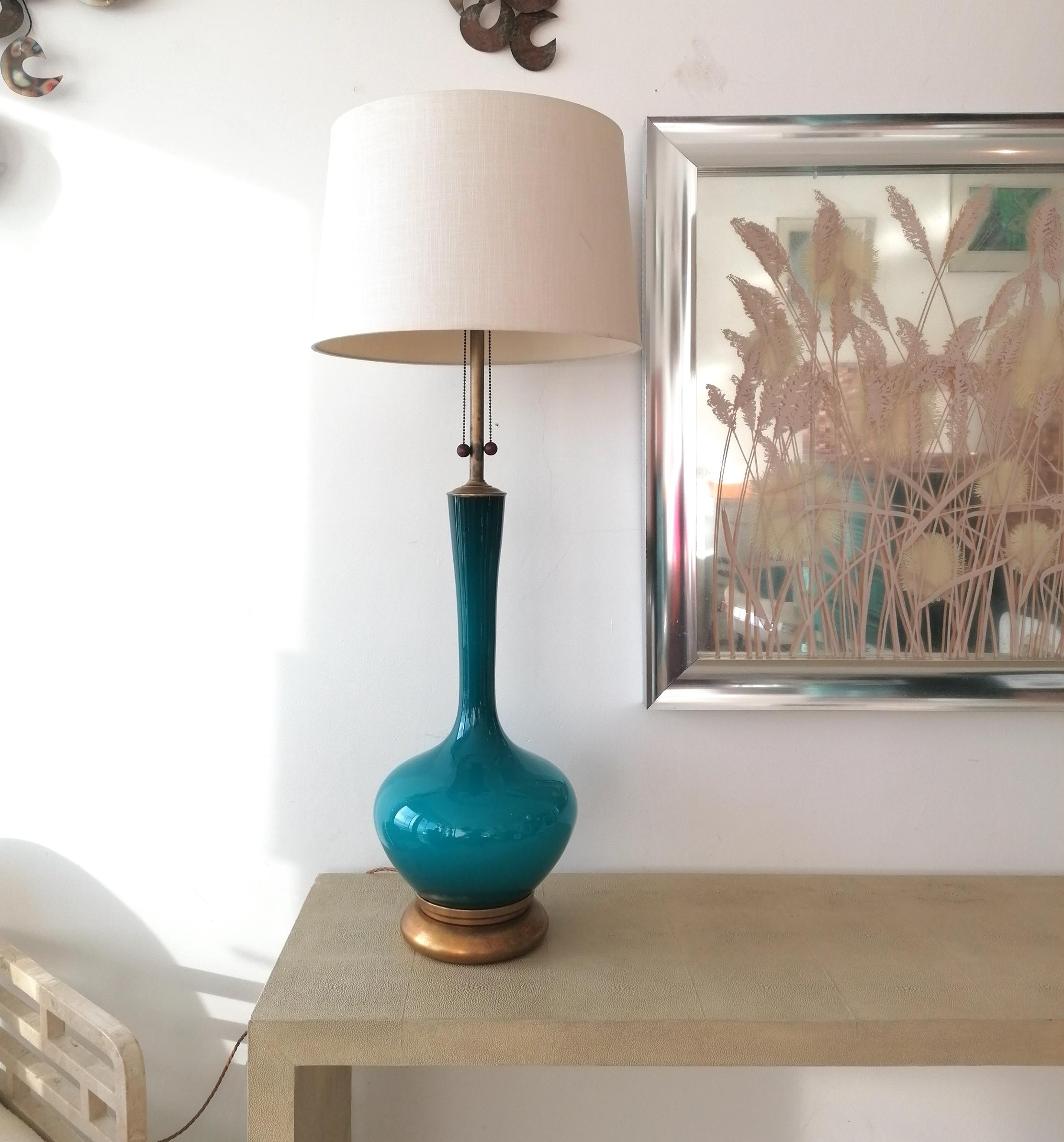This rare tall table lamp was produced for the Marbro Lamp Company, USA in the 1960s. The vivid semi-translucent peacock blue glass body was hand-blown in Sweden. The base is the original gilt wood & all fittings are solid brass. The double bulb