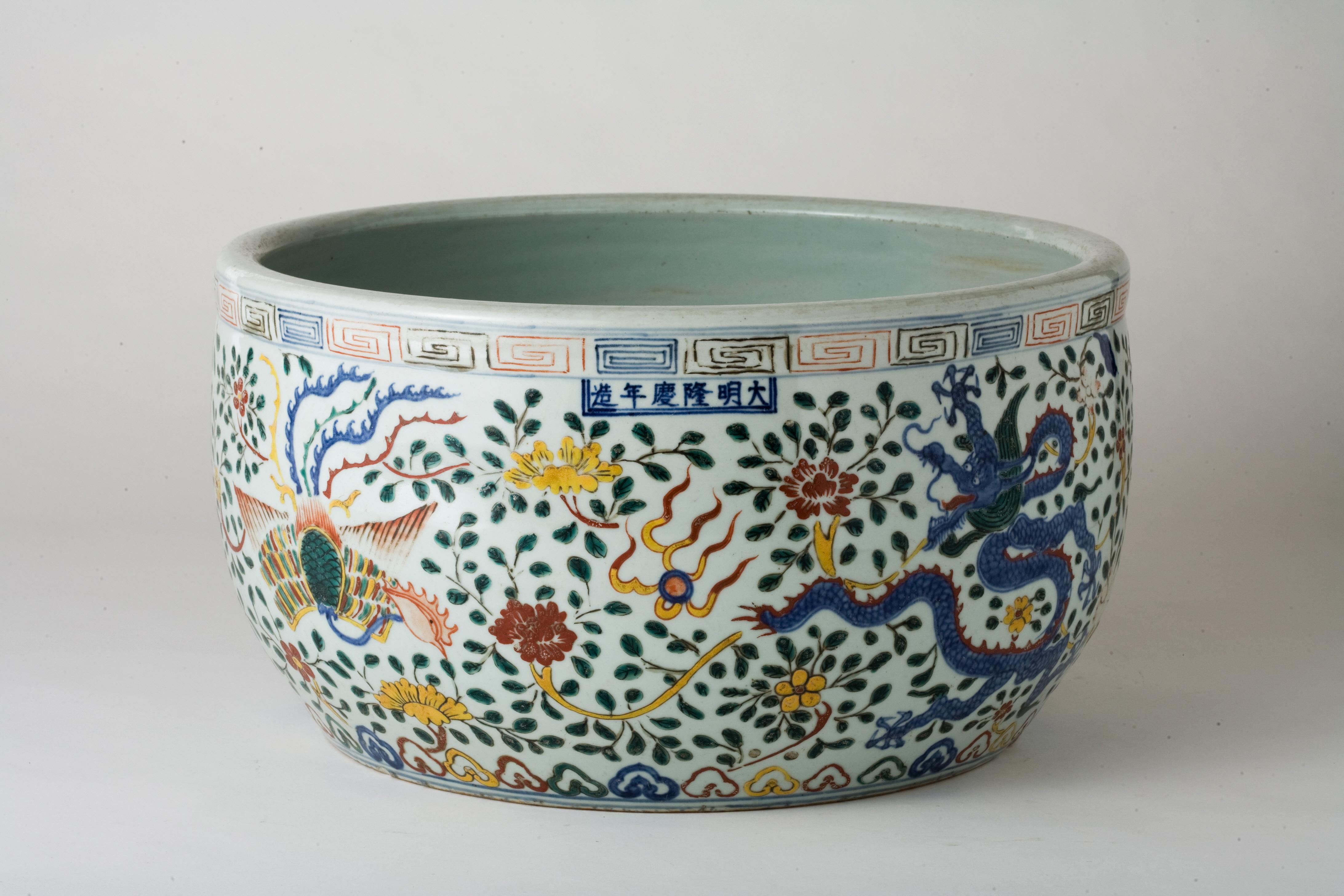 The blue dragon and the red dragon are depicted in dynamic postures, each extending its claws to grasp a ruyi pearl (如意珠). The phoenix is adorned with flowing feathers and delicate coloration. Around the dragons and phoenix, vibrant petals appear to