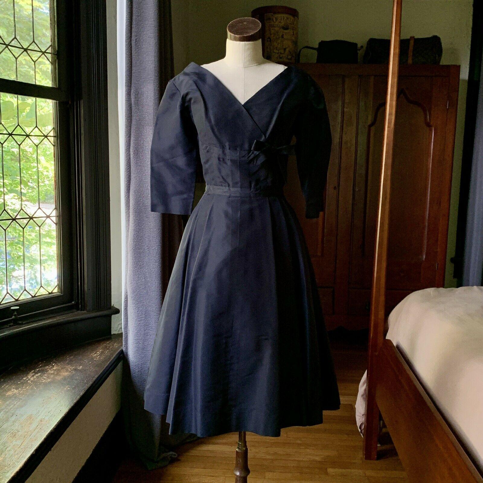 Larry Aldrich, 1950's Era Vintage Couture, Silk Taffeta, V Neck Front Wrap Style with Bow, Two Front Pockets, Nine Fabric Back Buttons, Built-in Moderate Crinoline with Hook and Eye Closures

Measurements Laying Flat

Bust 18