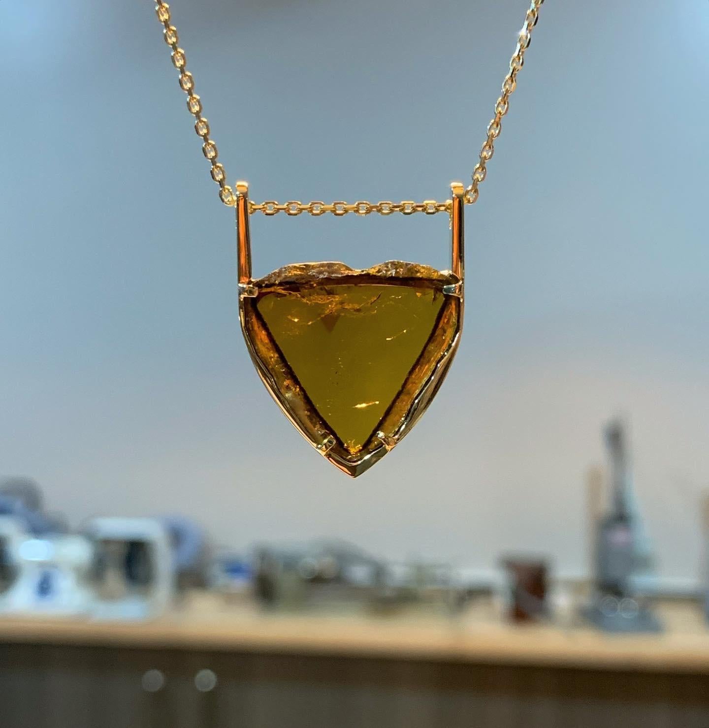 Ce collier en or jaune 18 carats, unique en son genre, est composé d'une magnifique tourmaline Liddicoatite de couleur ambre, qui cache un secret !  

Pouvez-vous repérer le petit triangle rose naturel à l'intérieur de la gemme ?  Cette