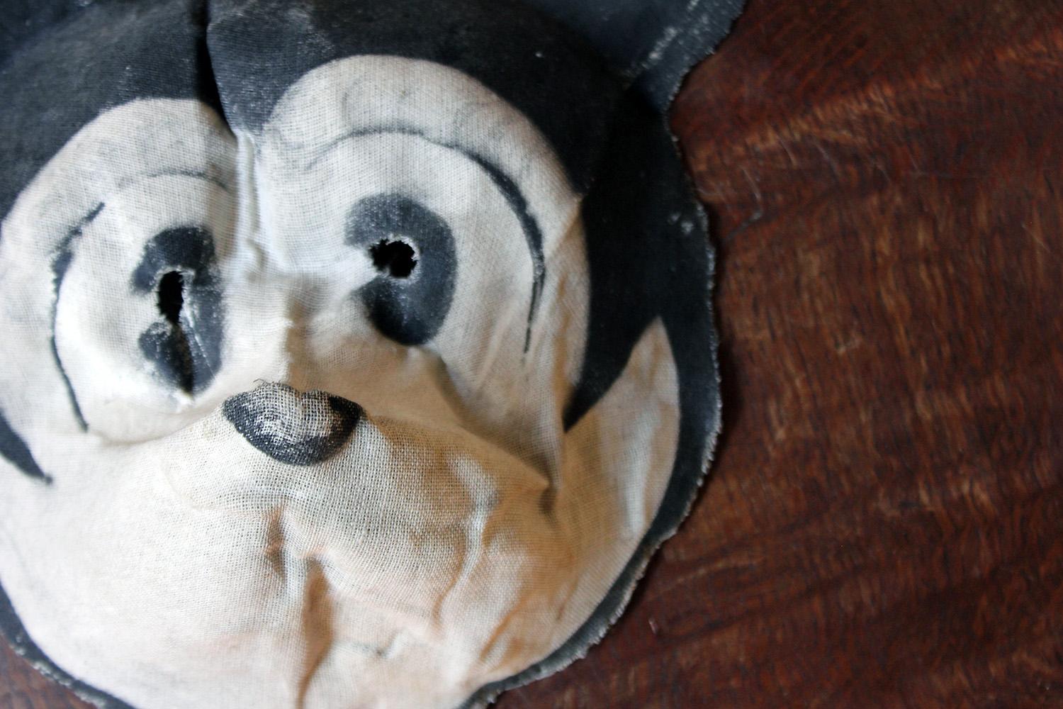 The scarce child’s Mickey Mouse mask in moulded linen with painted features, showing a red ink retail stamp to the interior with pierced holes and surviving in sound overall order, probably from Germany.

The ephemeral nature of the mask means it