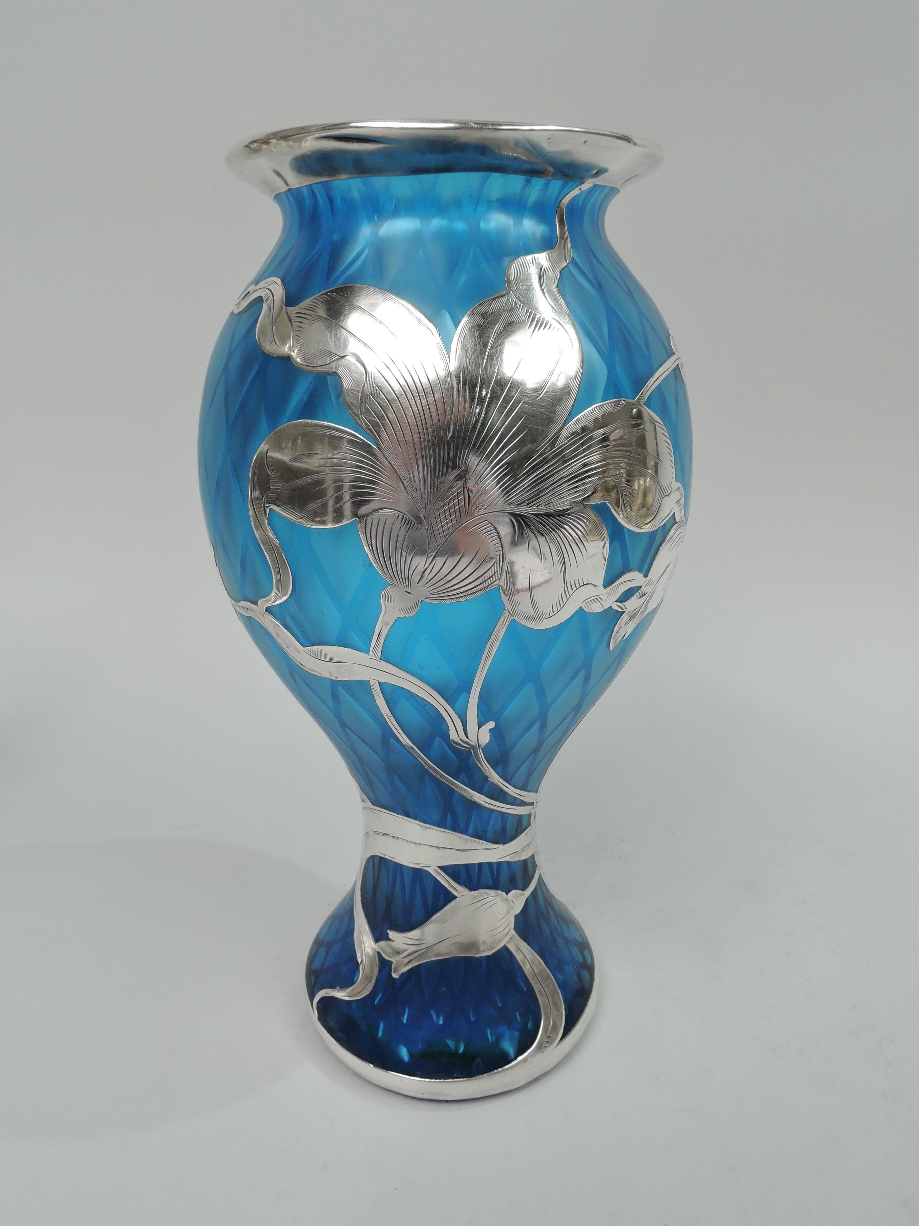 Rare and beautiful turn-of-the-century Art Nouveau glass vase by historic maker Loetz with engraved silver overlay. Steep baluster with flared rim and spread foot. Loose and fluid floral overlay. An open and dynamic design with irregular petals and