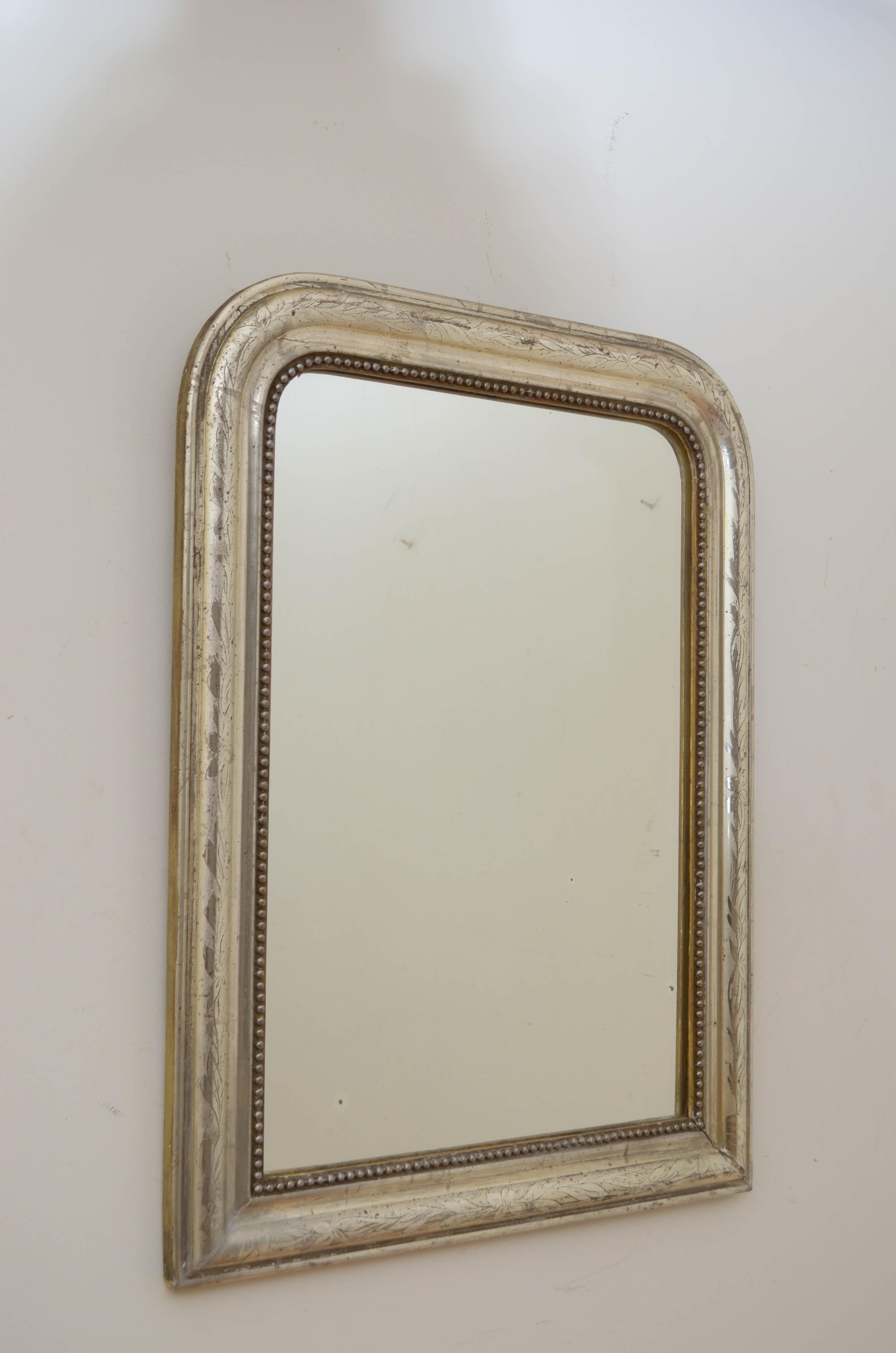 K0555 Beautiful 19th century silver gilded wall mirror, having original foxed glass in beaded, moulded and silver gilded frame with leaf motifs throughout. This antique mirror retains its original glass, original gilding and original backboard, all