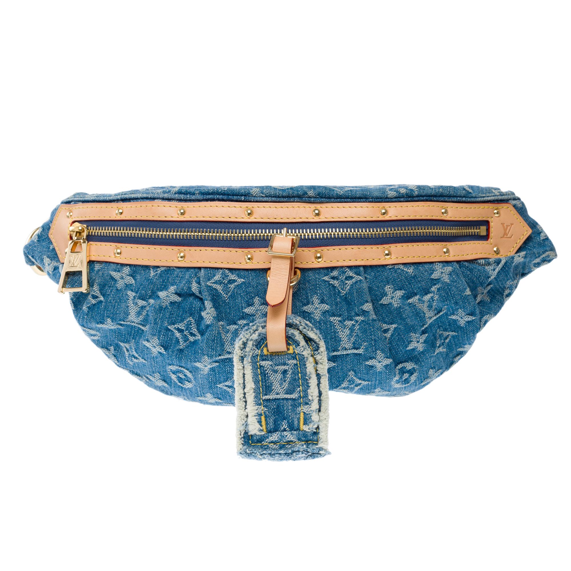 Made​ ​from​ ​blue Monogram​ ​Denim,​ ​the​ ​Louis​ ​Vuitton​ ​High​ ​Rise​ ​bumbag​ ​is​ ​trimmed​ ​with​ ​natural​ ​leather.​ ​Notably​ ​around​ ​the​ ​zipper,​ ​where​ ​the​ ​cowhide​ ​is​ ​adorned​ ​with​ ​golden​ ​studs.​ ​A​ ​removable​ ​name​