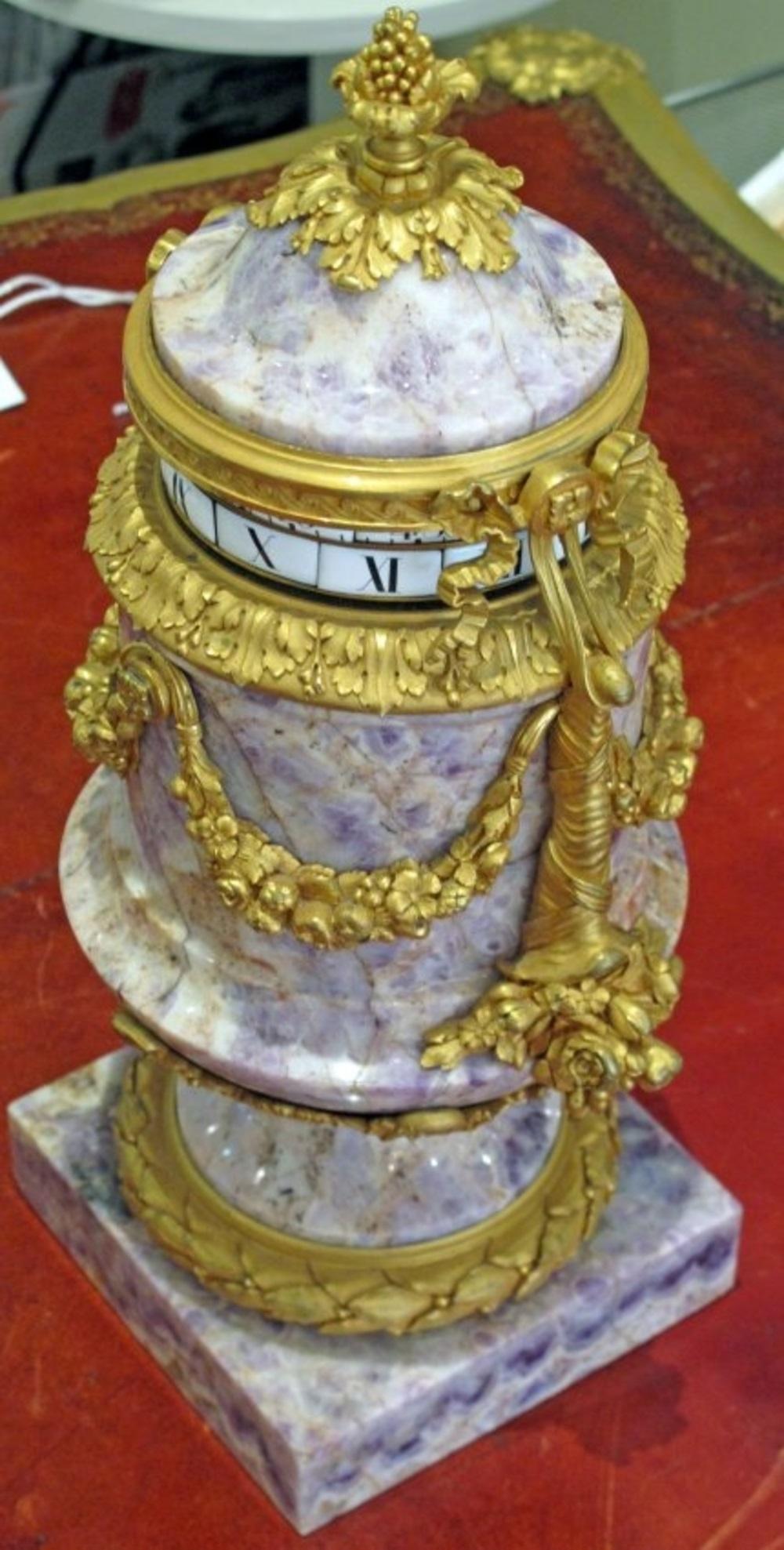 A superb and rare Louis XVI style gilt bronze mounted amethyst rotary clock
French, circa 1885, in the manner of Edward Minart
the urn form clock case with porcelain dials and white enamel chapters flanked by a pair of handles with a laurel swag
