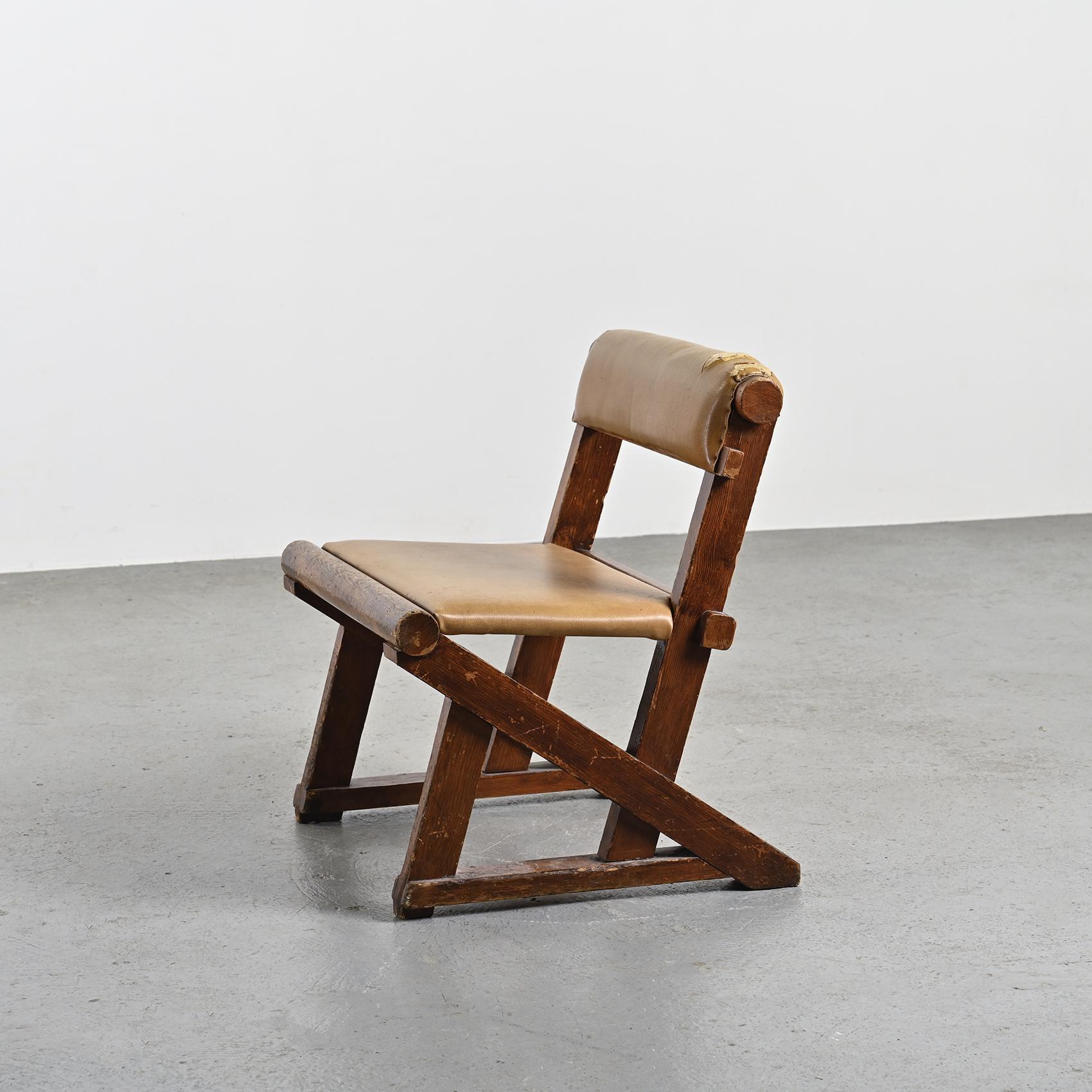 Rare lounge chair in dark-stained pine, distinguished by its robust wooden sections connected by cylindrical logs. These rounded elements, positioned at each end, elegantly frame the seat and enhance the backrest, both upholstered in tawny-colored