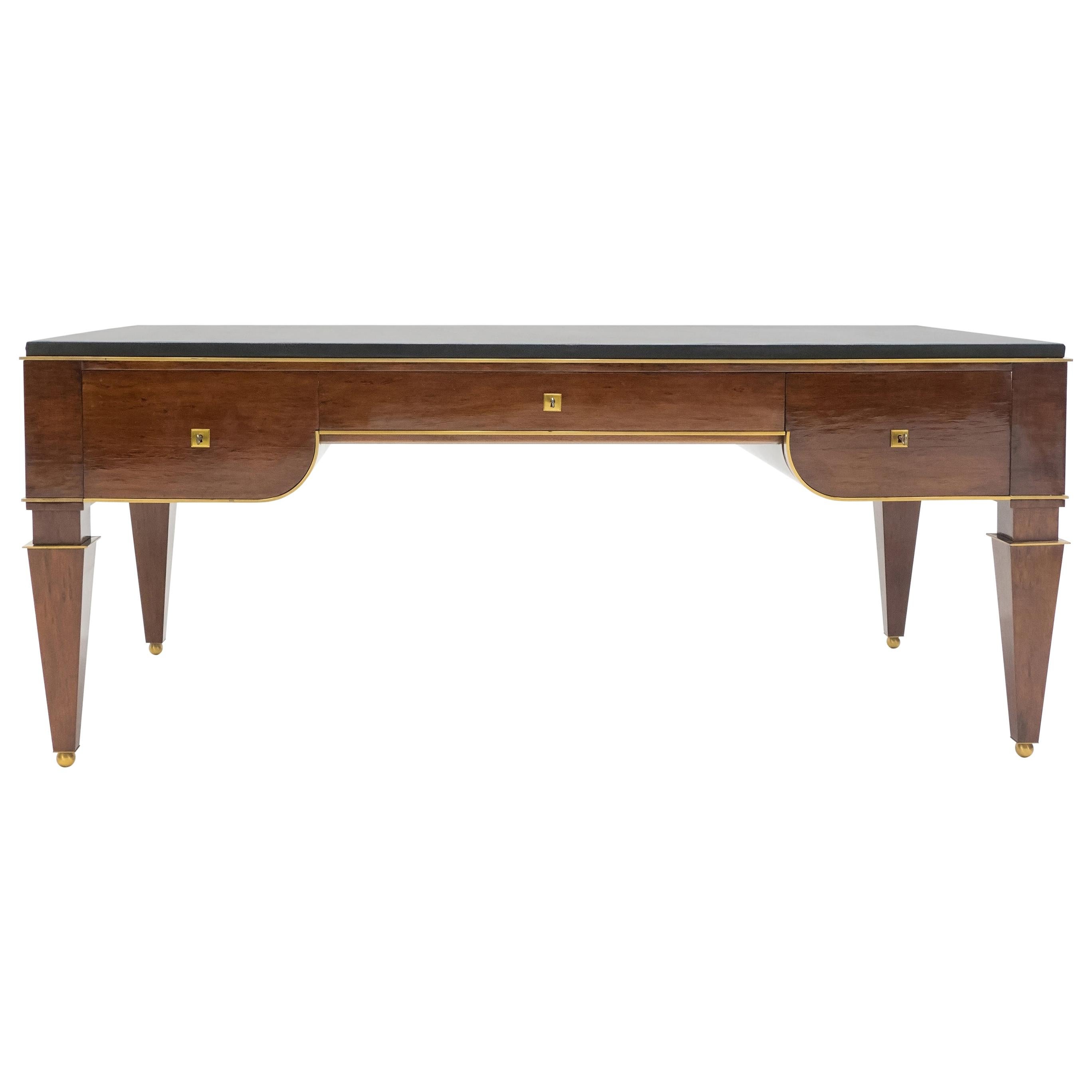 This rare and beautiful French neoclassical was made in the early 1940s, and is attributed to Maison Dominique. The woodwork, pure line and brass accents and details are just wonderful. It features a full black leather top, with three large drawers