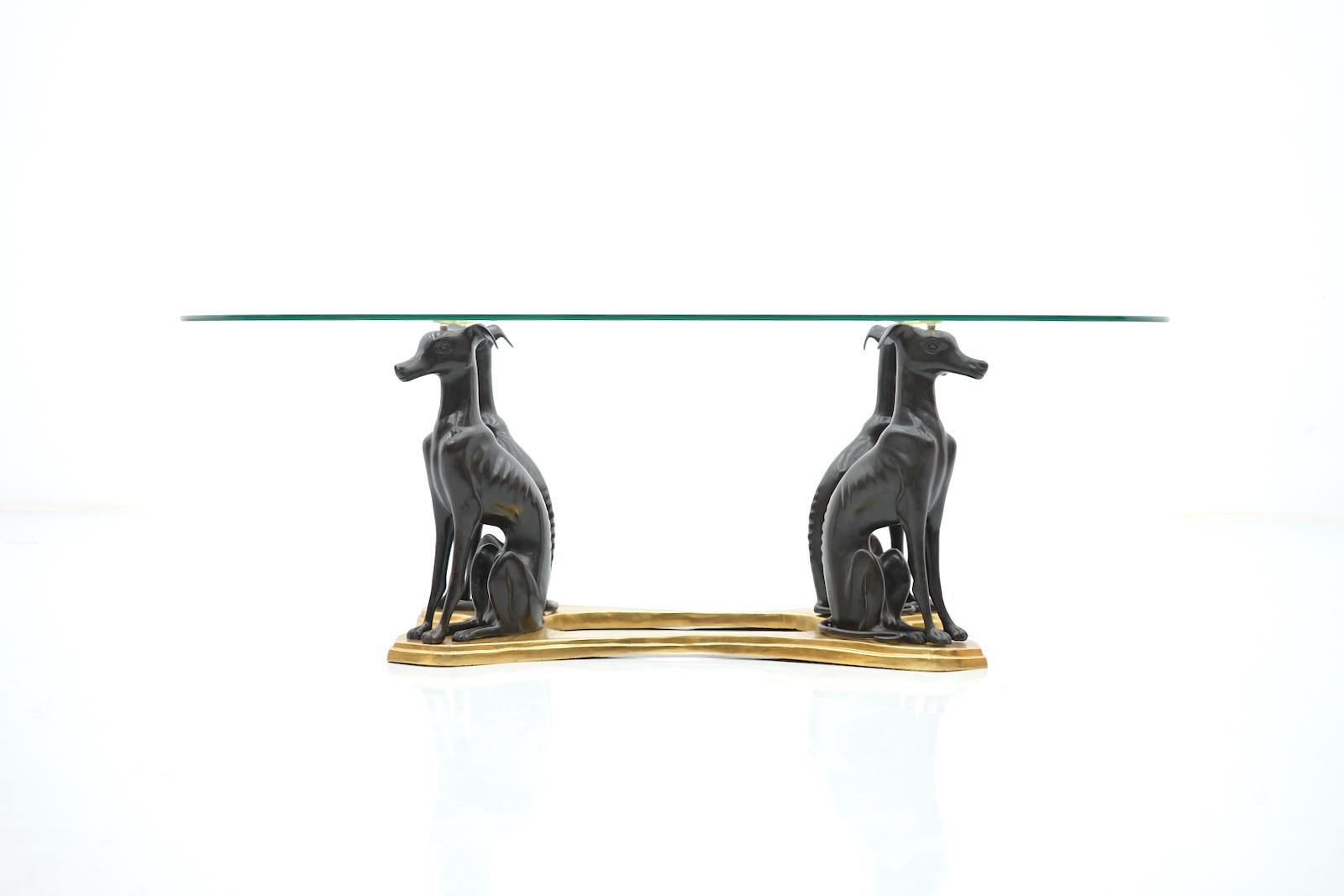 Rare coffee table of Maitland - Smith with four Greyhound Dogs. More often on the market are these tables with only 3 dogs. 
The table frame and the dogs are made of brass. The oval glass top with faceted cut edge.
The table is in very good