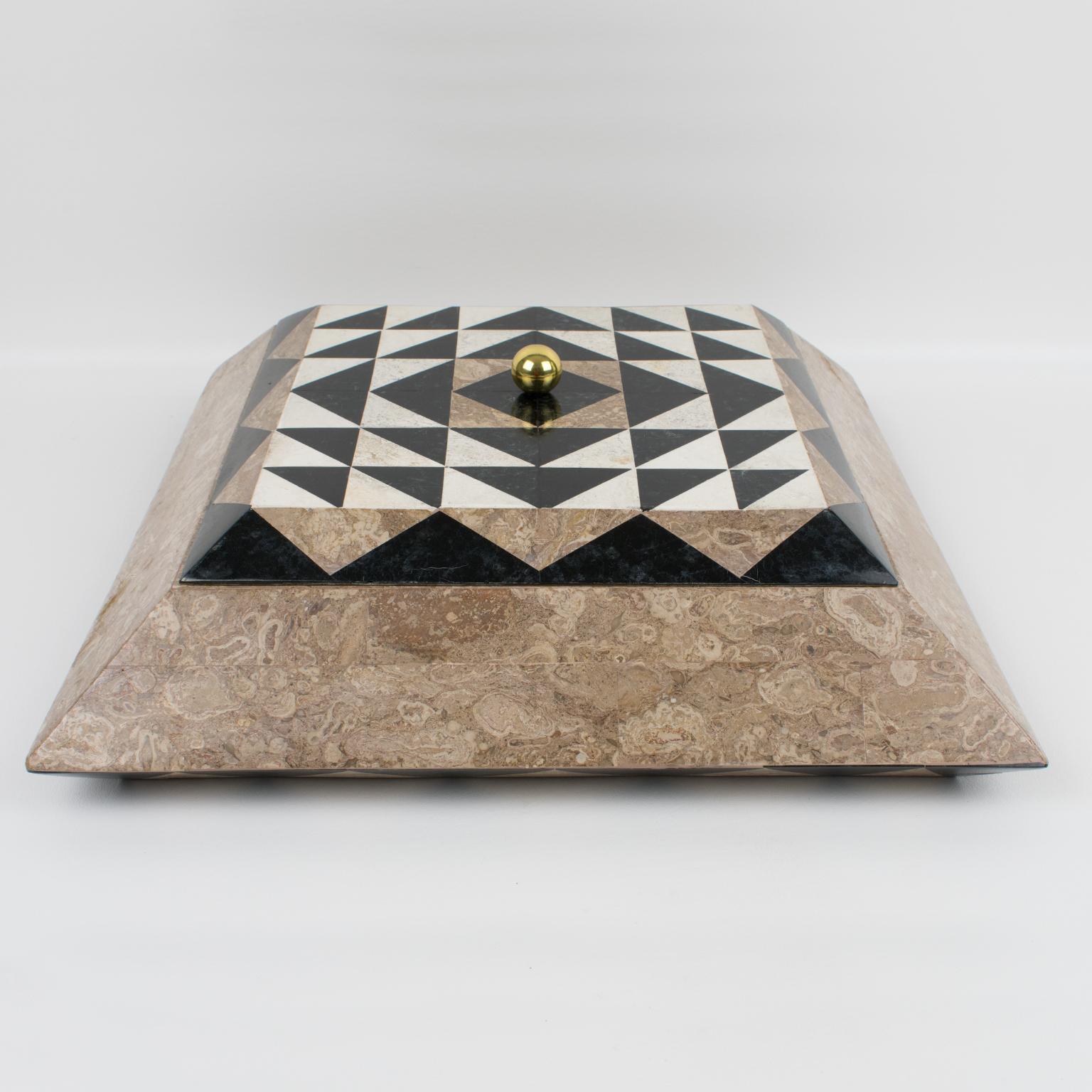 Maitland Smith diseñó esta espectacular caja con tapa. La pieza se fabricó hacia 1980. La caja presenta una composición teselada de mármol, piedra, travertino y latón. El diseño piramidal de forma cuadrada presenta colores beige arena, negro y