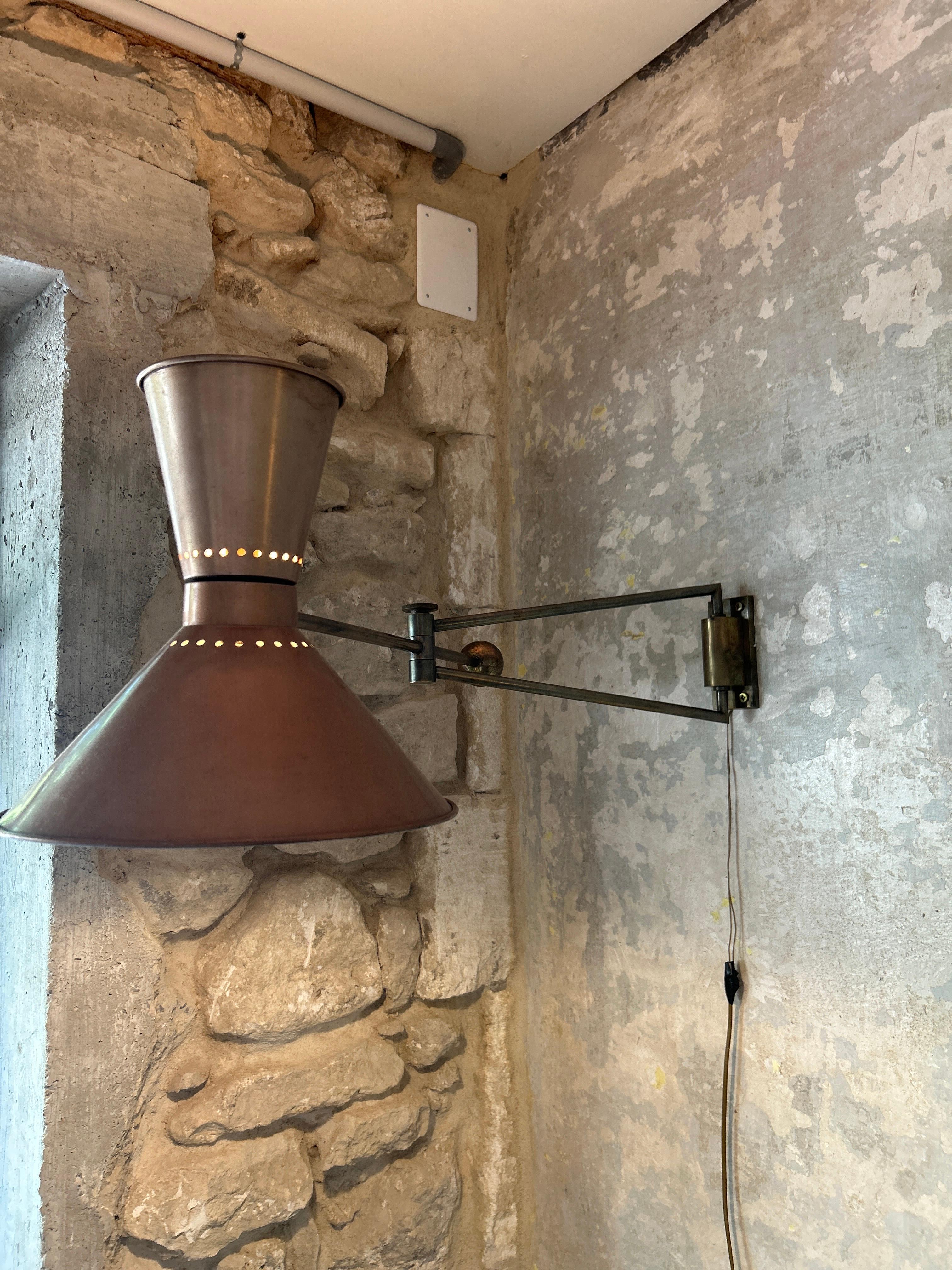 MARCEL ASSELBUR (1910-1964) 
Articulated wall lamp with double orientation, tubular shaft with gunmetal patina, biconical perforated deflector with copper patina, counterweight, adjustable ferrule and brass mounting plate.
In working order 
Good