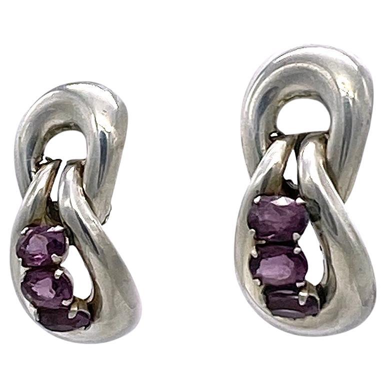 Se trata de un par de pendientes de clip de plata de ley Marcel Boucher de la década de 1940, cada uno con tres piedras de cristal amatista facetadas engastadas. Estos raros pendientes de bisagra están firmados en la parte posterior del clip por