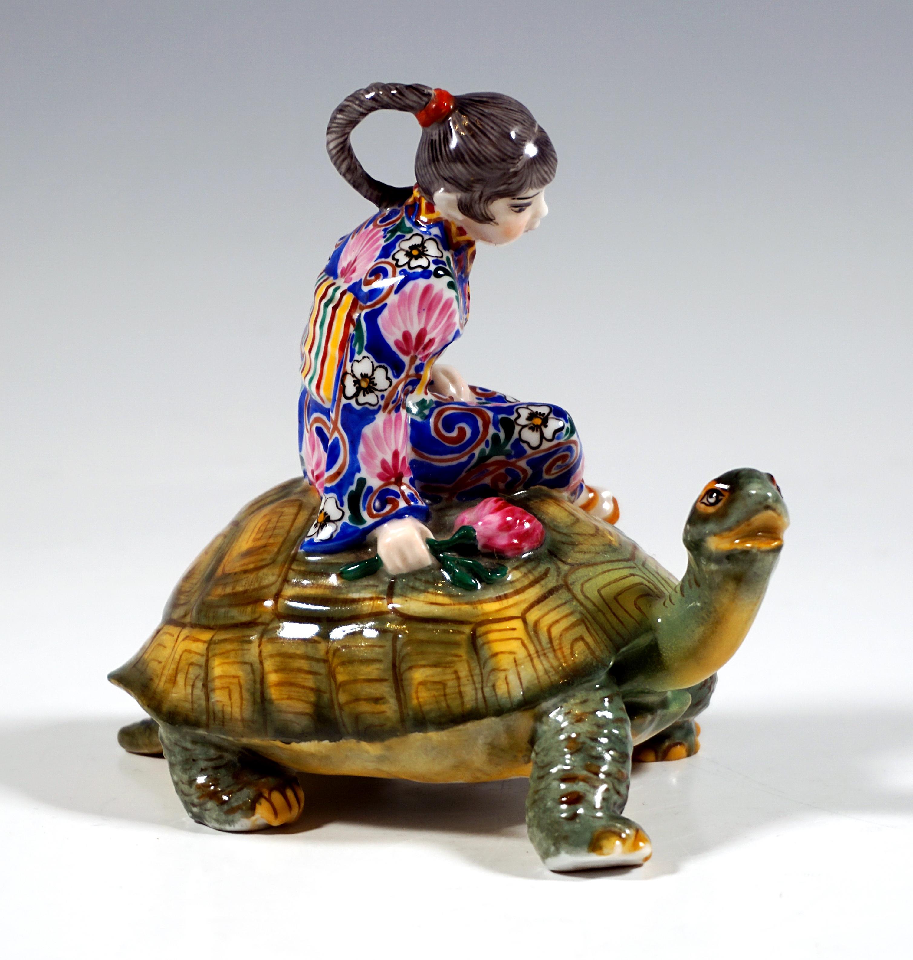 Exceptional Marcell Goldscheider Art Déco porcelain figurine group:
Japanese girl with her hair plaited into a long, tight plait, wearing a traditional robe - kimono with elaborate floral decoration, belt and thong sandals, sitting sideways on the