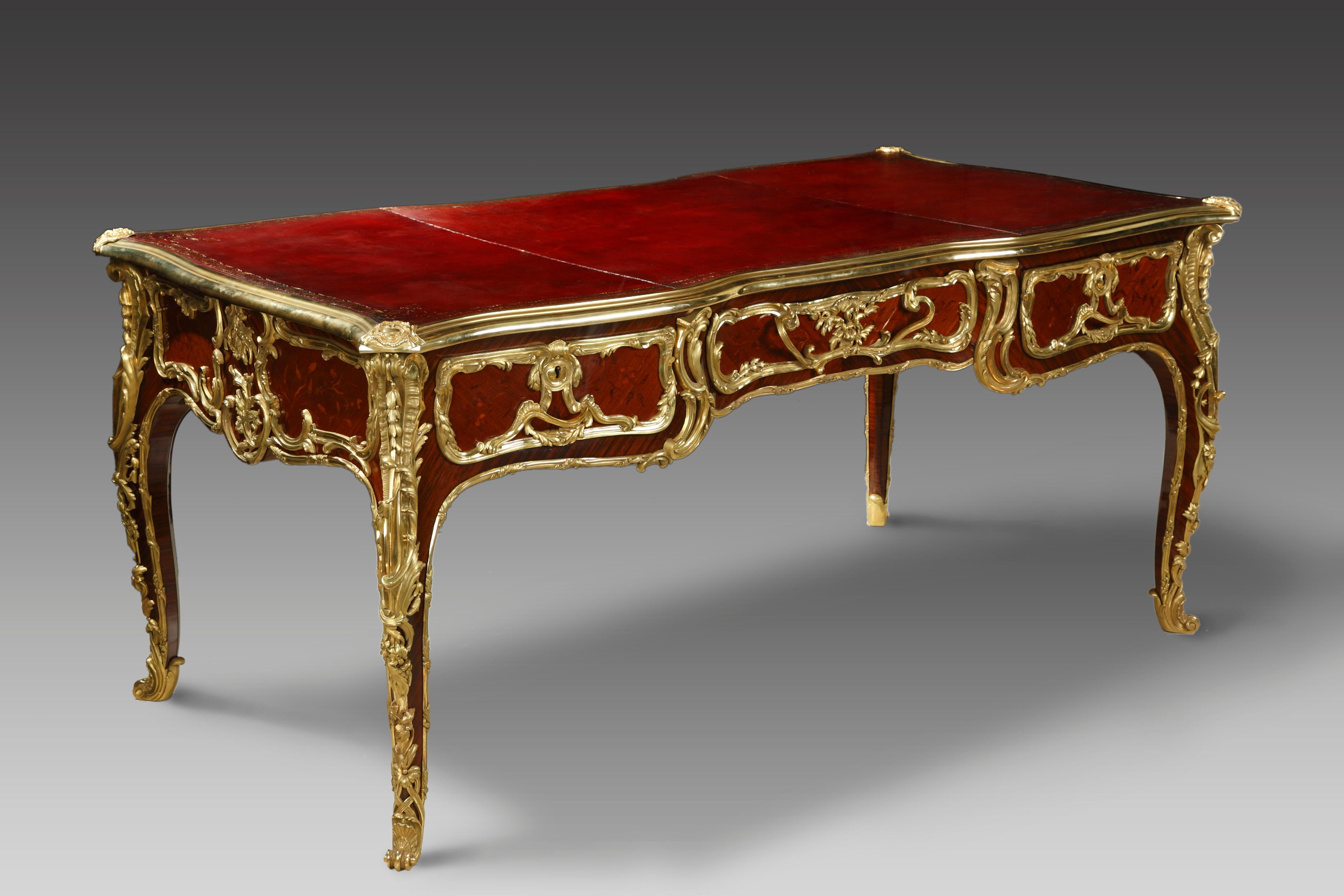 Rare bureau plat double face de style Louis XV, en bois plaqué, ouvrant à trois tiroirs décorés d'une belle marqueterie de bois en bout à motif de fleurs. Avec des enrichissements en bronze finement ciselés et dorés, composés de motifs rococo. Il